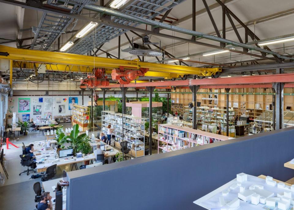 Spacious interior of a Dutch architect's studio featuring workstations, bookshelves, and architectural models, showcasing creative design work.