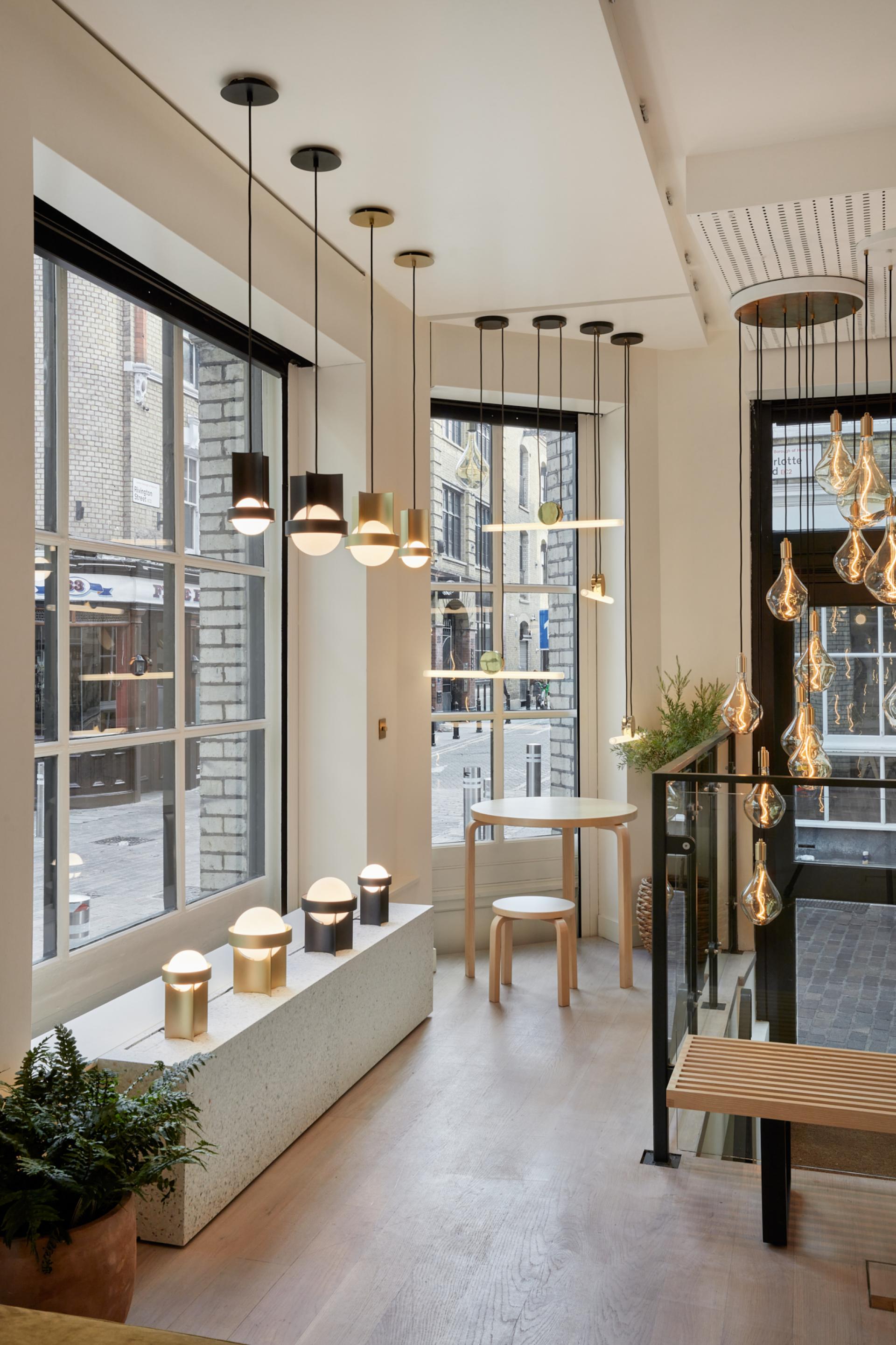 Modern Shoreditch showroom featuring Tala's sustainable lighting designs, including pendant and table lamps, with natural decor elements.
