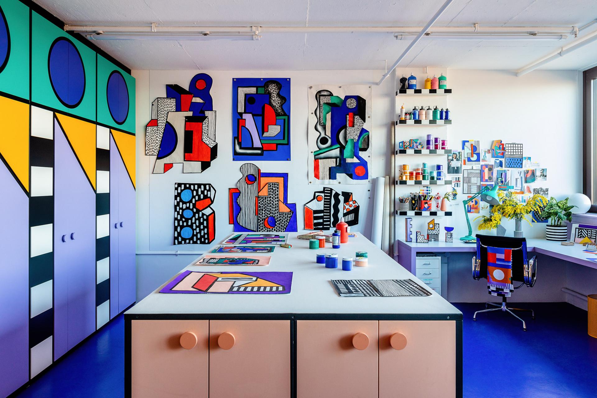 Vibrant art studio featuring bold geometric designs, colorful paint supplies, and unique wall artworks in a bright environment.