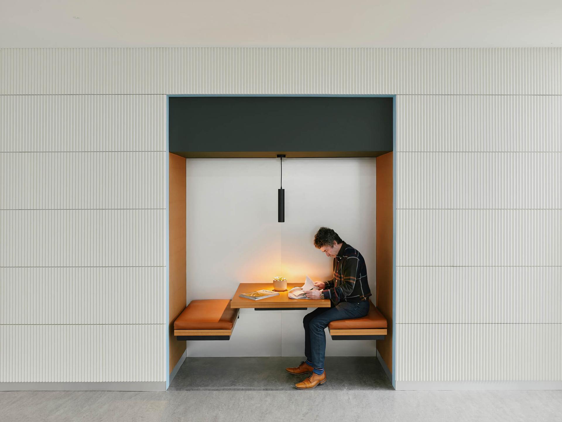 Modern workspace interior at Manchester International Office Centre featuring seating and a man studying at a wooden table.