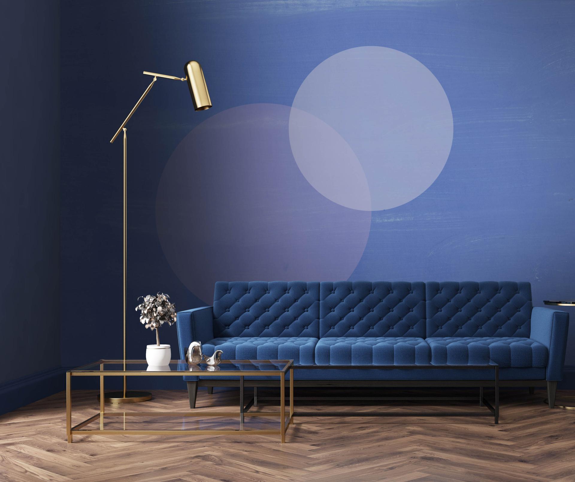 Luxurious commercial interior featuring a blue tufted sofa, elegant floor lamp, and modern accent table against a textured wall.