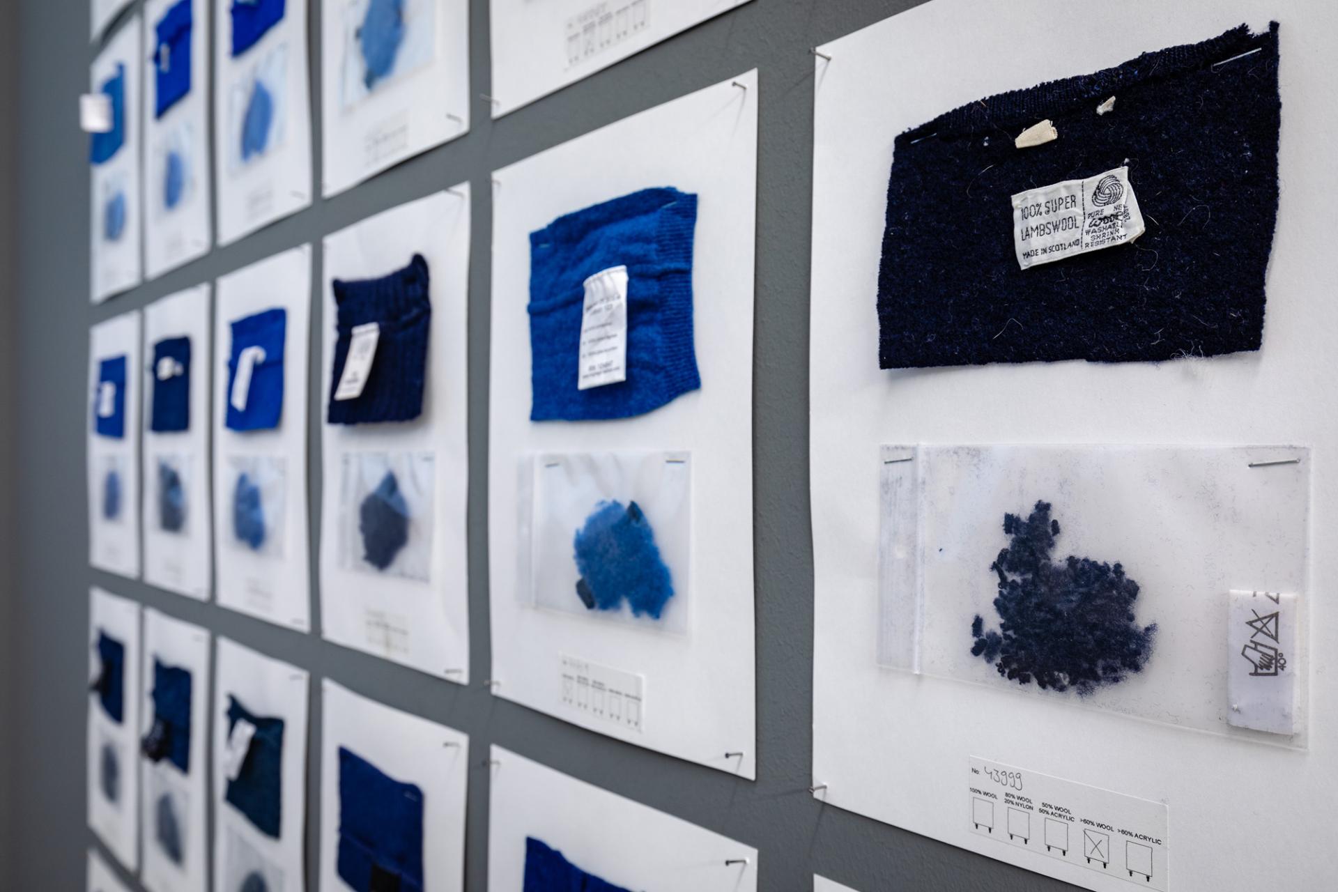 Samples of blue textile materials displayed on a wall, illustrating Christien Meindertsma's focus on sustainable design processes.