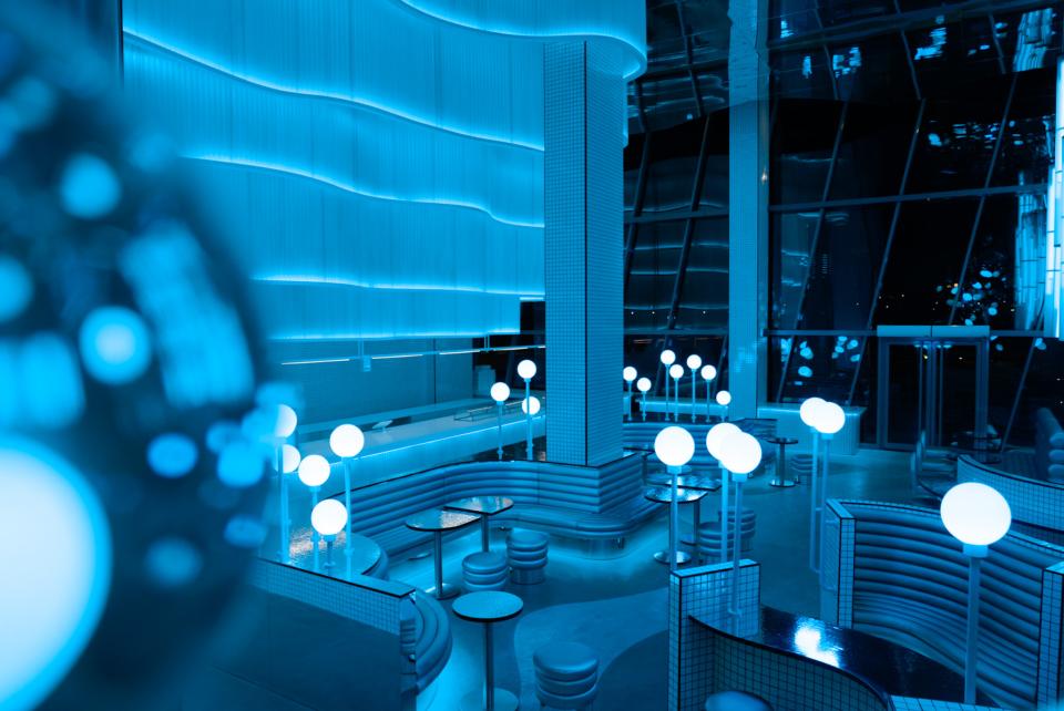 Vibrant blue interior of MO, a modern bakehouse and espresso bar, featuring circular light fixtures and sleek seating.