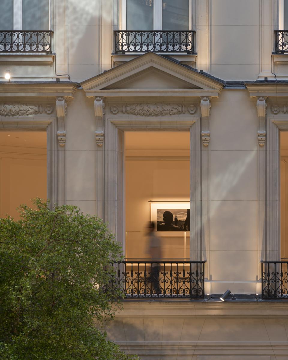 Elegant façade of Apple’s Champs-Élysées store, featuring intricate Parisian architectural details and a visitor on the balcony.