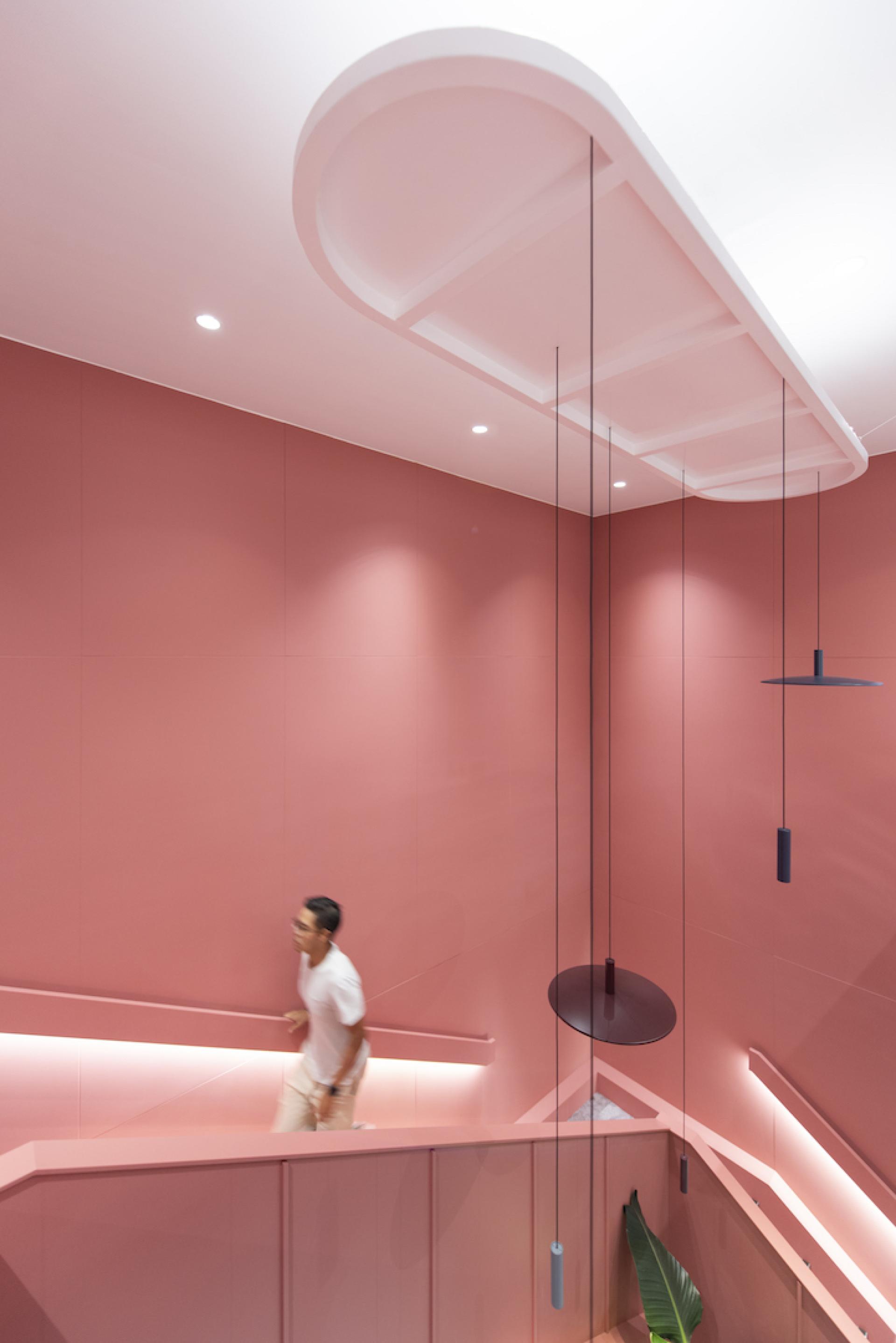 Modern stairwell design featuring warm pink tones and stylish lighting for Jardine Restaurant Group's agile workspace by Bean Buro.