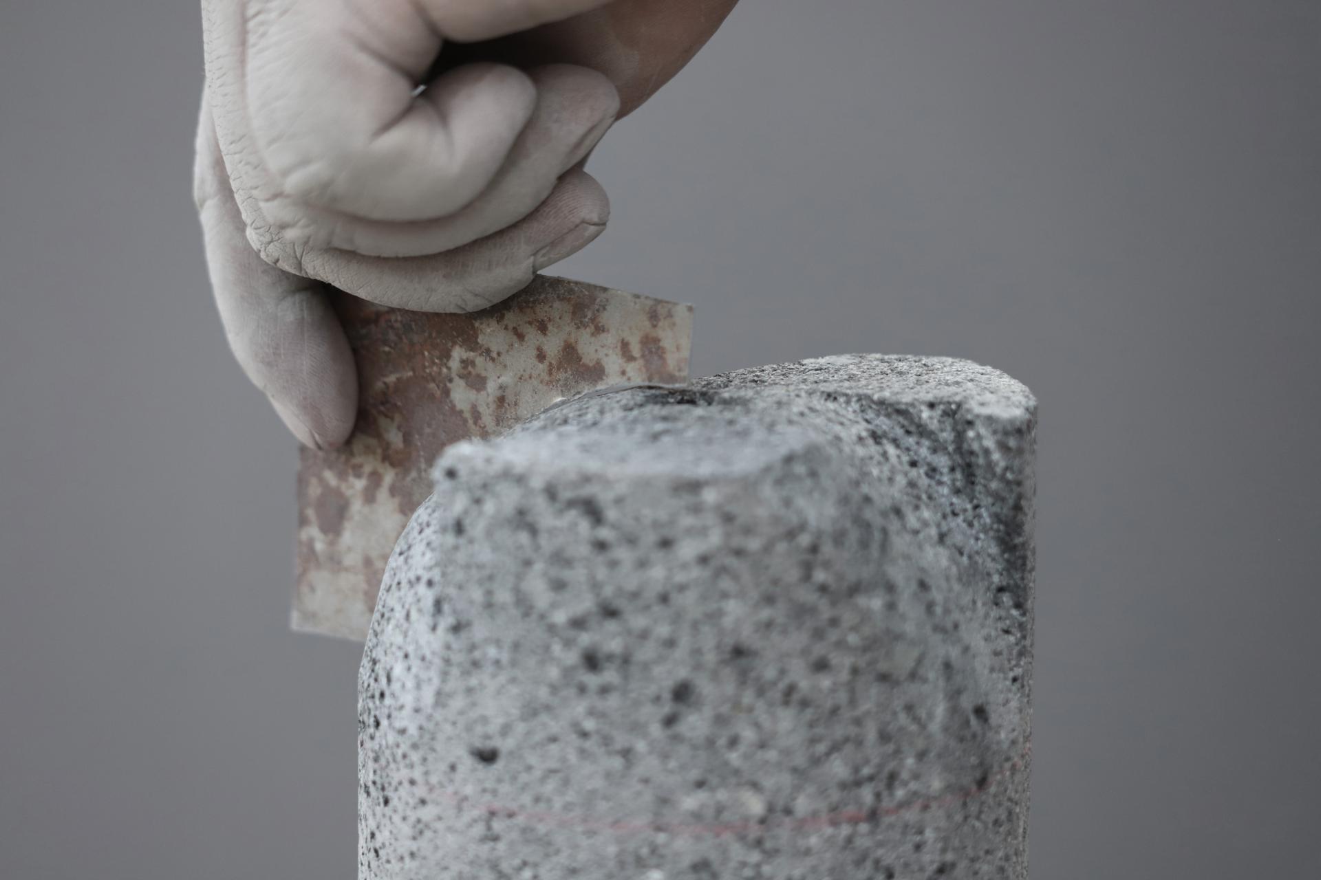 Artisan shaping of new Meta collection finishes, featuring textured gray material and a tools, highlighting craftsmanship in design.