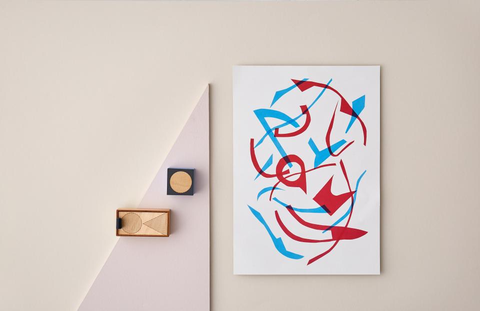 Abstract artwork featuring bold red and blue shapes alongside minimalistic wooden geometric objects, highlighting innovative design.