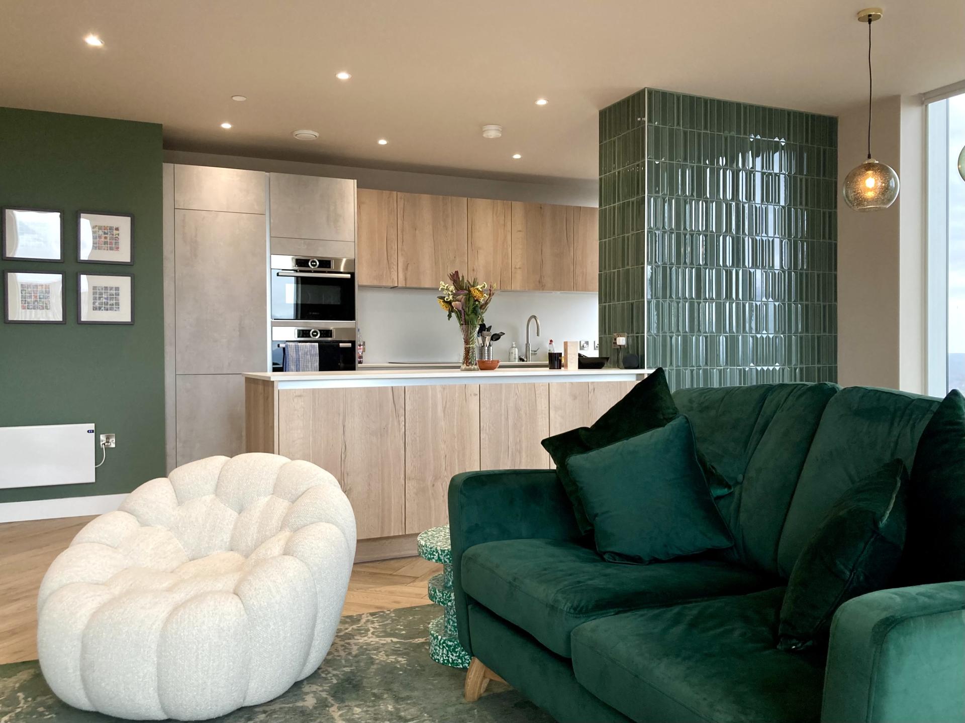 Modern Manchester kitchen with stylish green accents, featuring a cozy couch, textured walls, and elegant decor elements.