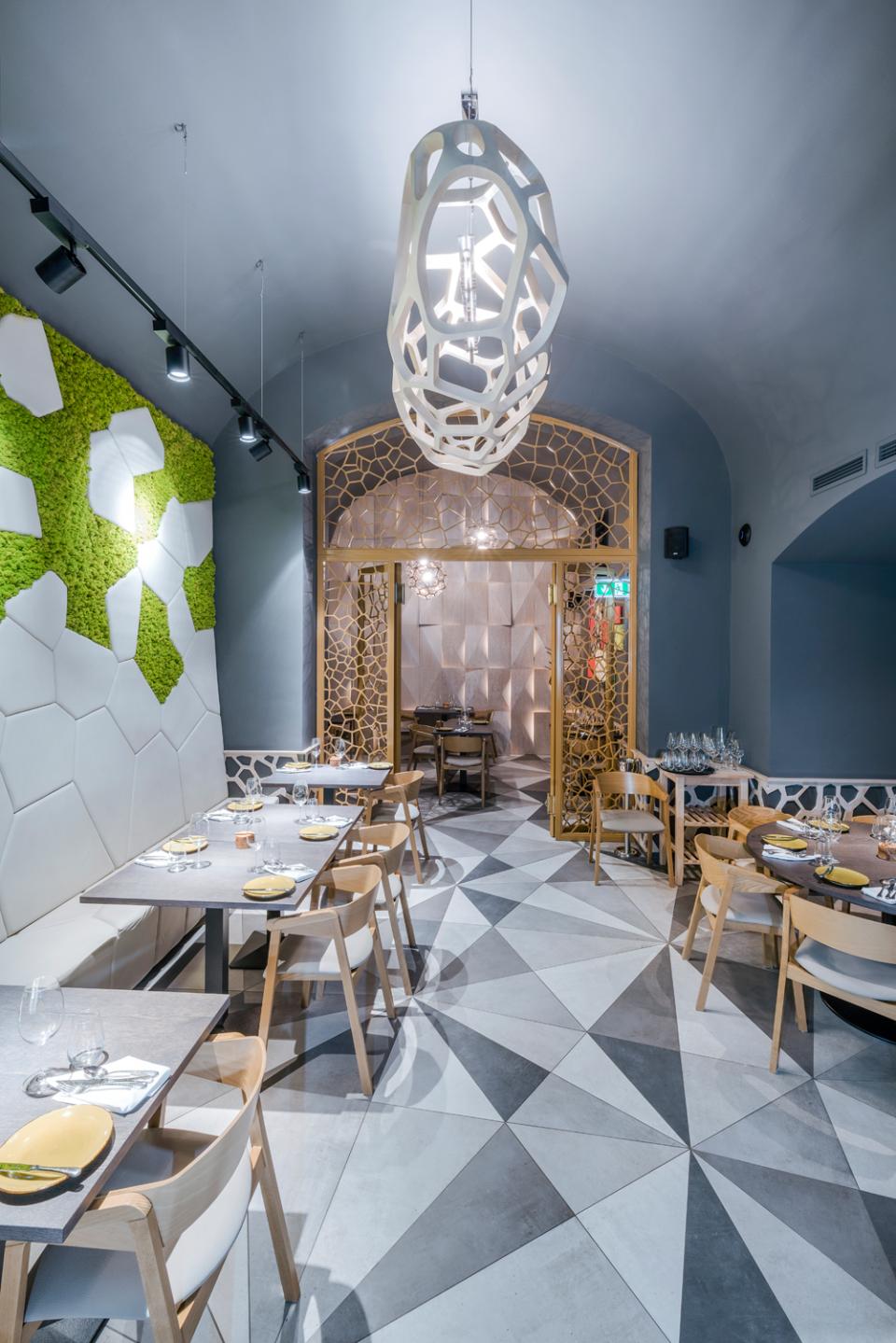 Modern restaurant interior featuring geometric design elements, a unique ceiling light, and a vibrant moss wall.