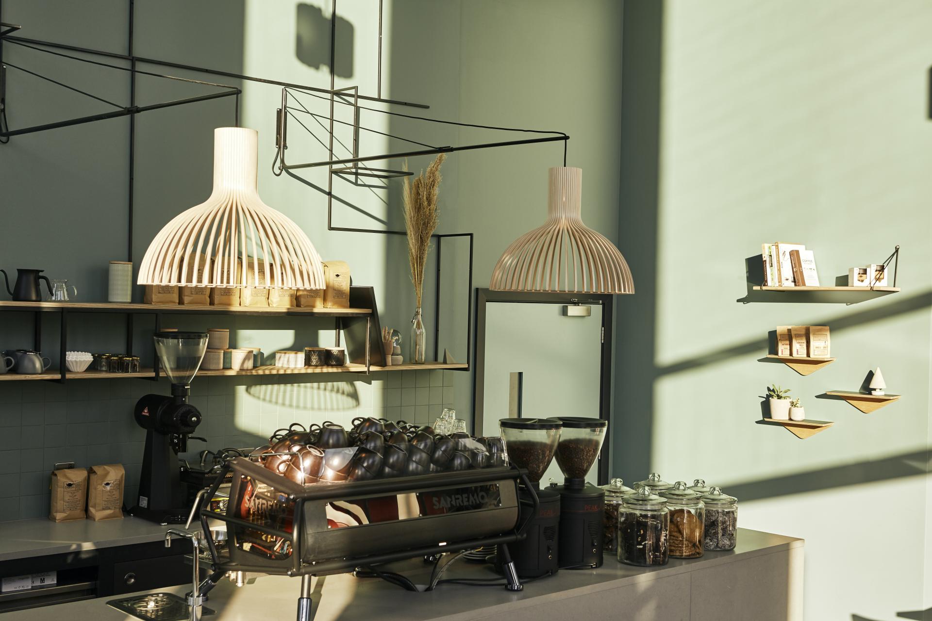 Artisan coffee shop featuring Caesarstone Raw Concrete countertops, modern decor, and stylish wooden light fixtures.