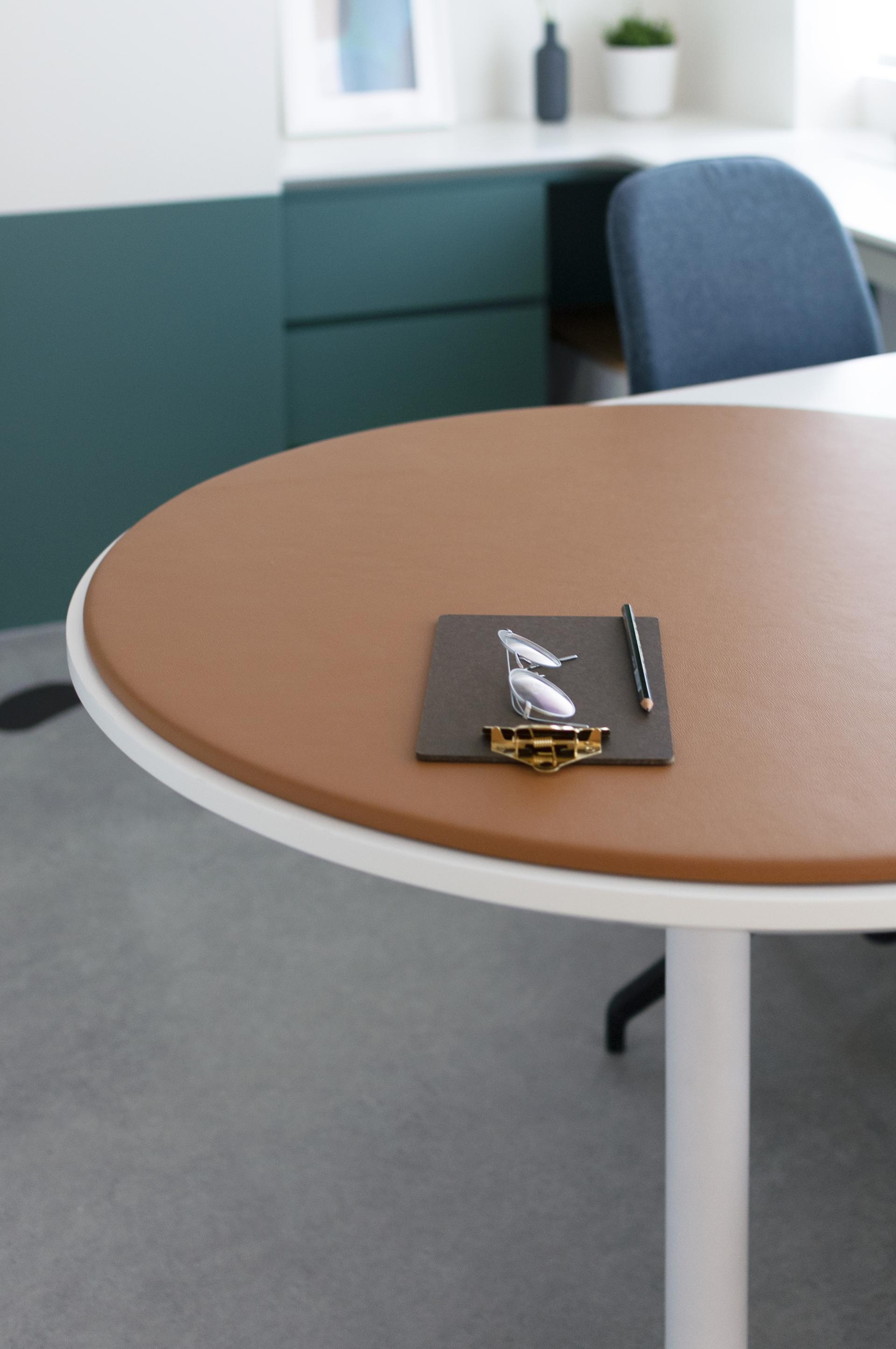 Modern clinic workspace featuring a round table with a clipboard, glasses, and pencil, designed for pediatric wellbeing.
