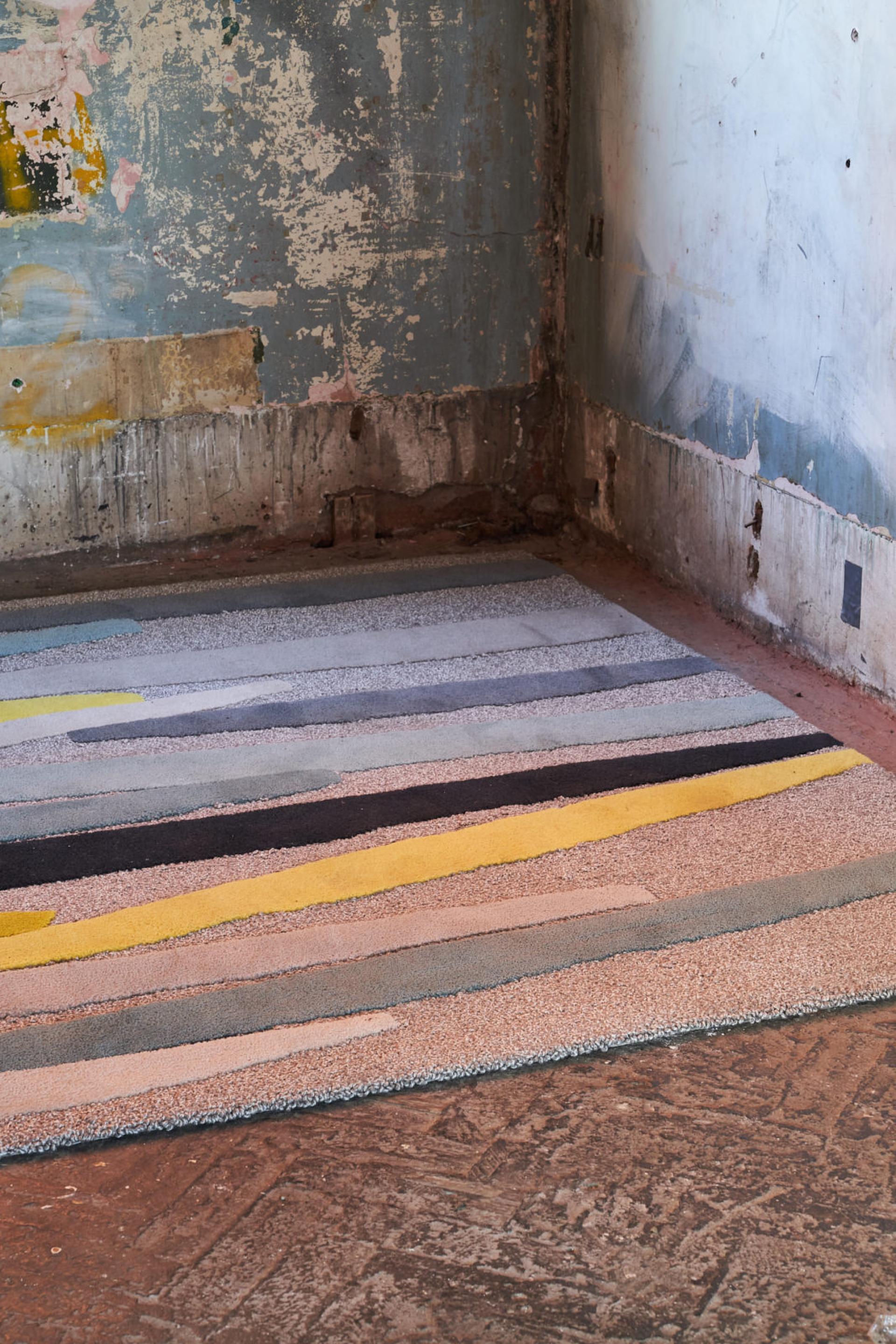 Colorful textile art installation on a textured floor, showcasing innovative craft design at London's Bargehouse.