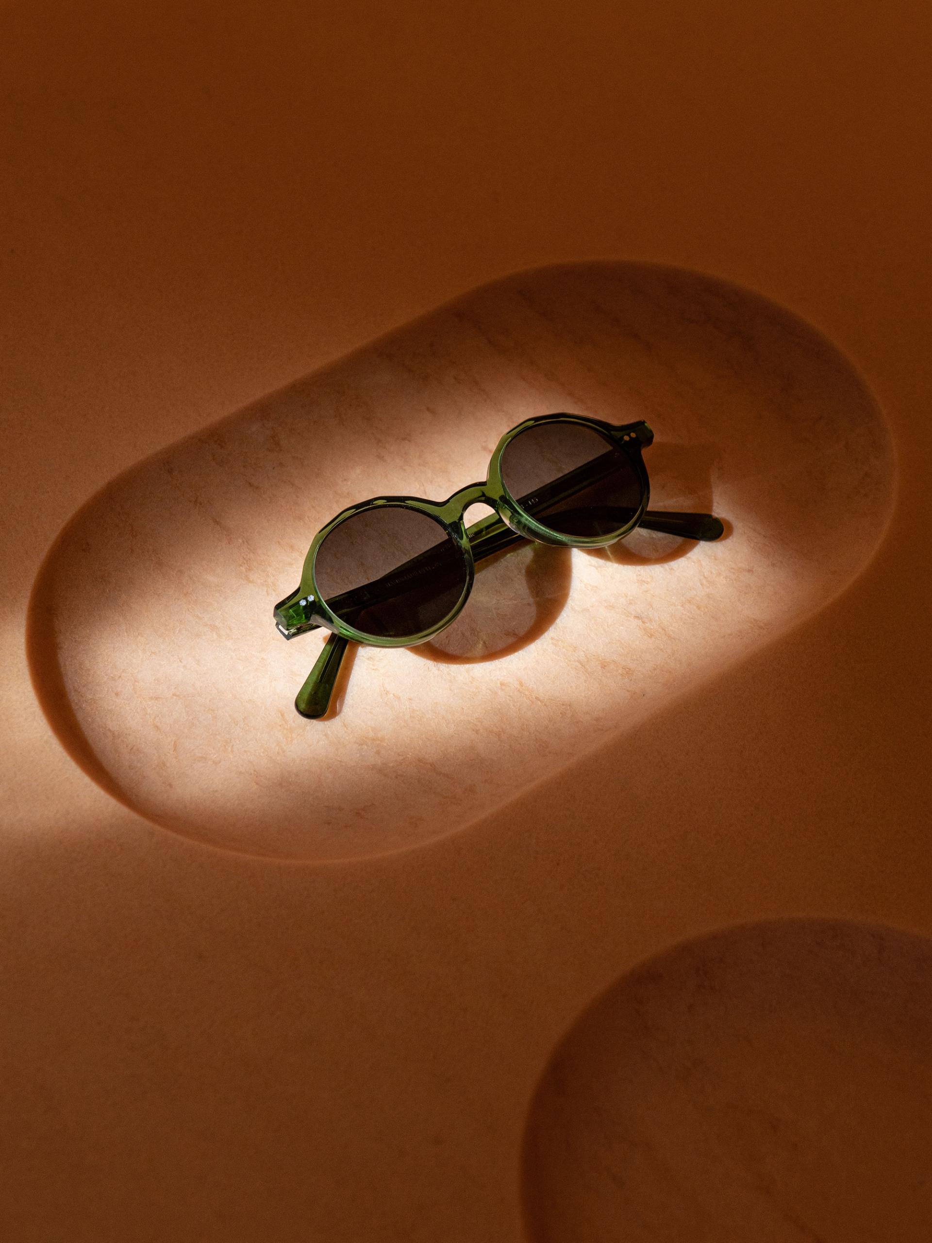 Sustainable green sunglasses showcased in a minimalistic display, highlighting MONC's zero-waste eyewear initiative.