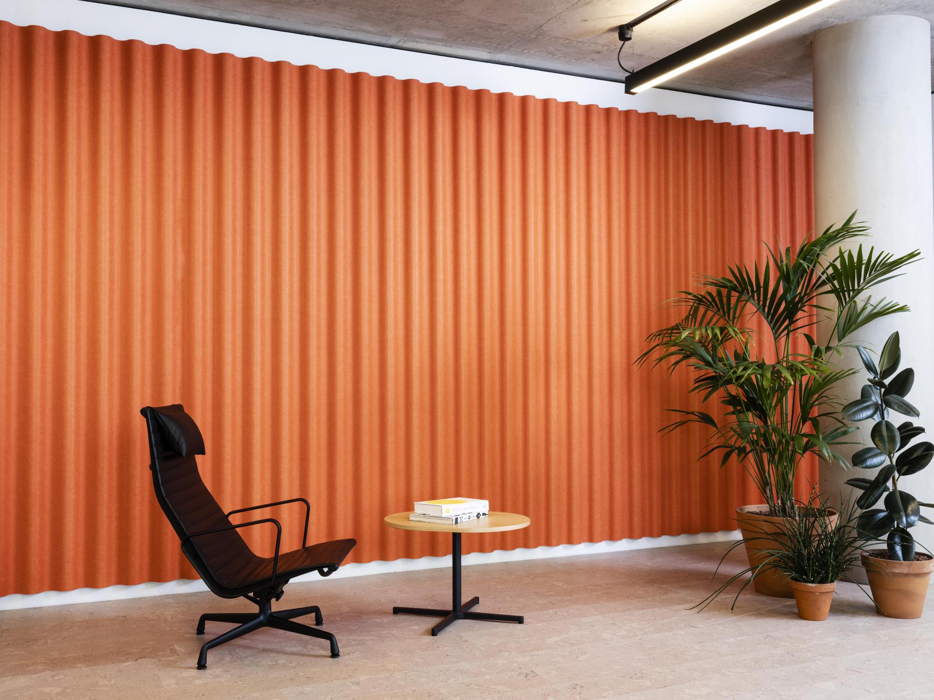 Stylish interior featuring Swell acoustic wall cladding in orange, complemented by modern furniture and greenery.