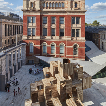 Aerial view of MultiPly, a carbon-neutral wooden pavilion made of American tulipwood, against a historic building backdrop.