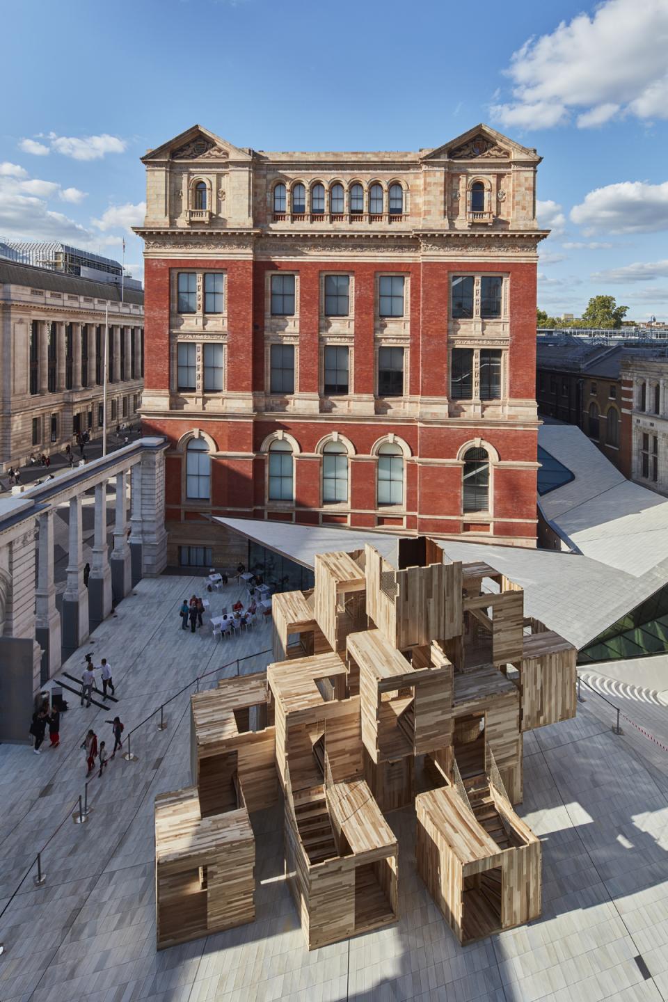 Aerial view of MultiPly, a carbon-neutral wooden pavilion made of American tulipwood, against a historic building backdrop.