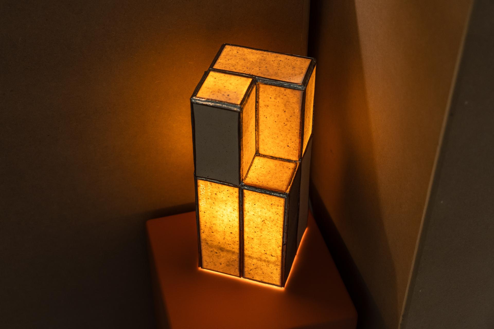 Sculptural lamp design showcasing bio-based materials, illuminated against a brown background at Material Source Studios exhibition.