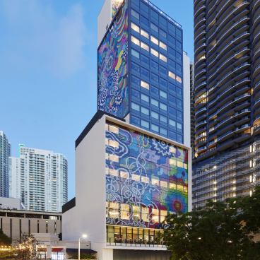 colorful exterior of citizenM hotel in Miami, showcasing vibrant artwork and modern architecture against a clear blue sky