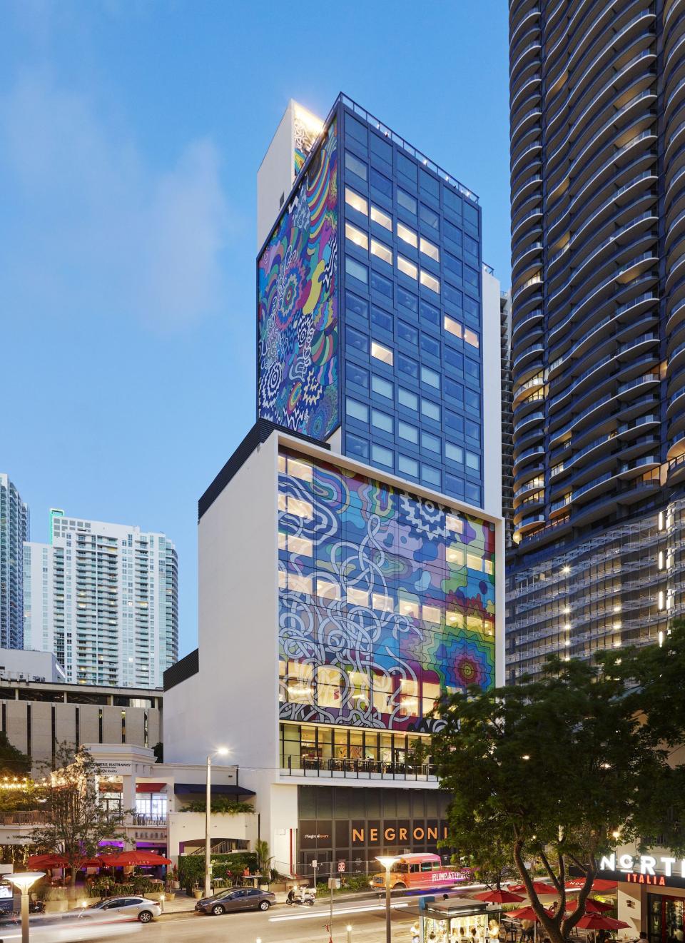 colorful exterior of citizenM hotel in Miami, showcasing vibrant artwork and modern architecture against a clear blue sky