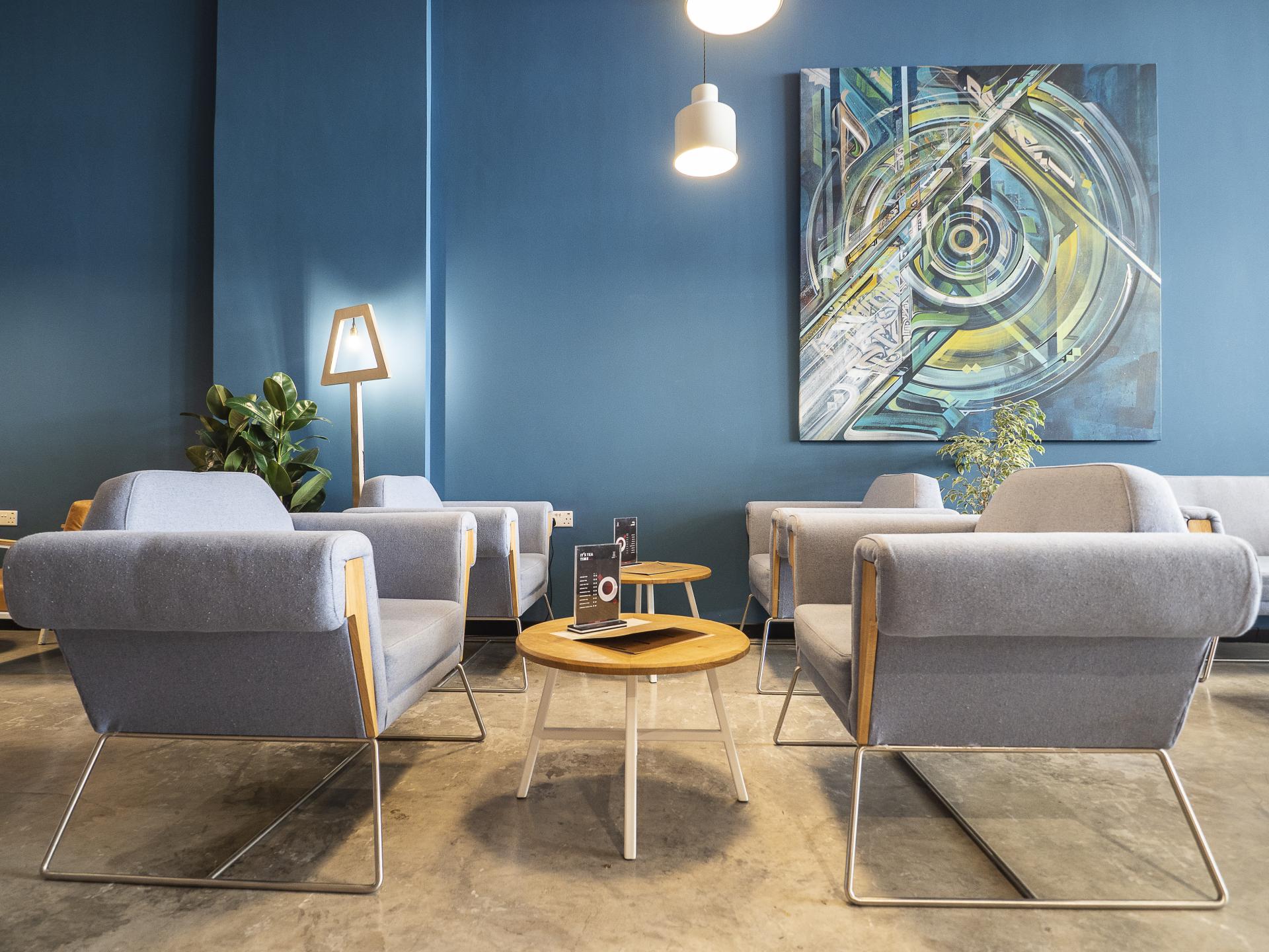 Modern seating area in Brew92 café featuring blue walls, artistic décor, and stylish furniture by Liqui Design.