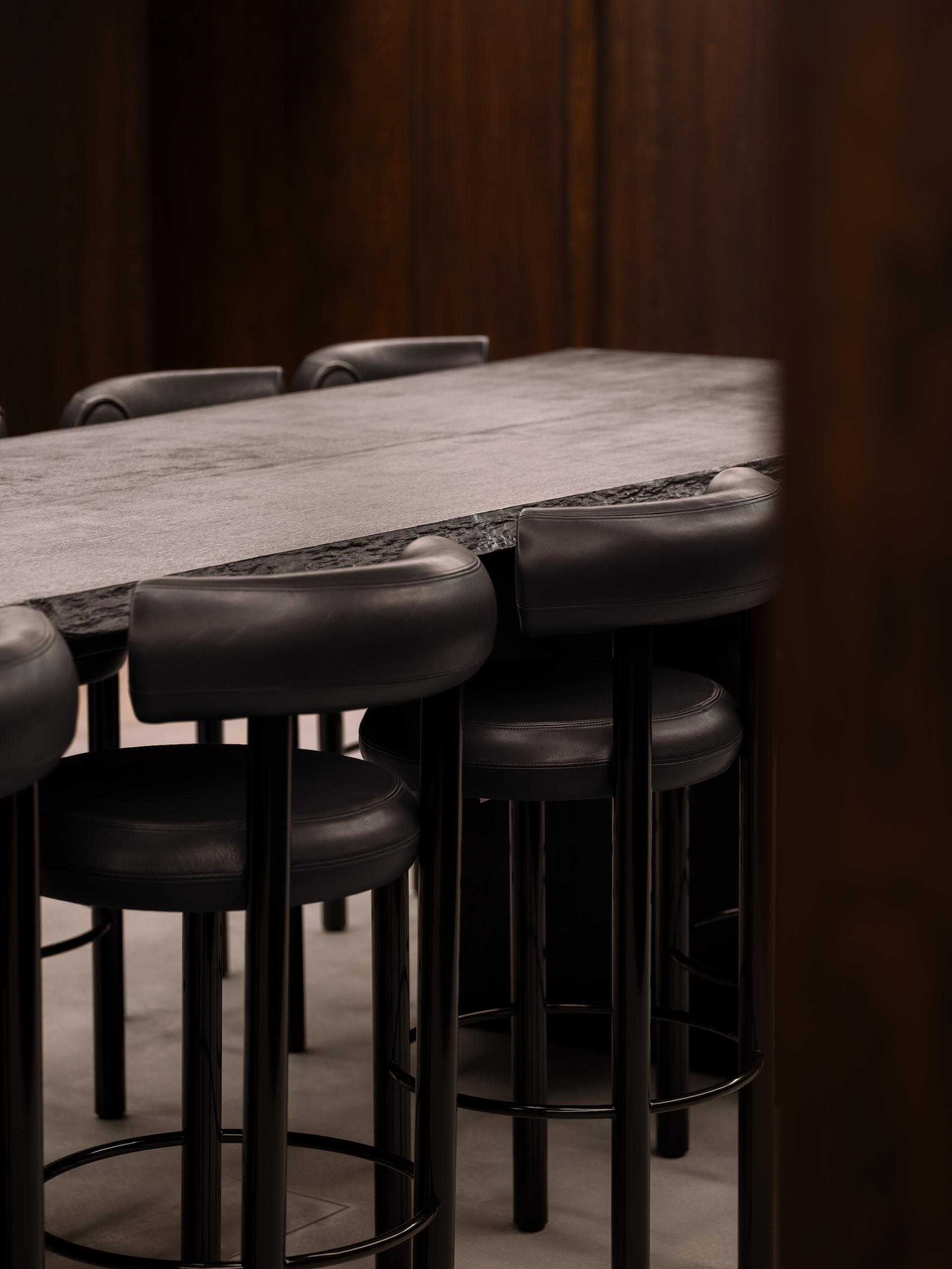 Modern bar seating with sleek black stools surrounding a minimalist stone table in KEF's Music Gallery London.