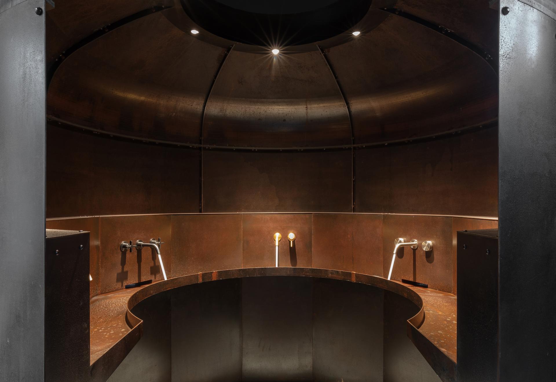 Innovative co-working space featuring a circular, industrial-style design with unique lighting and modern fixtures by Holloway Li.