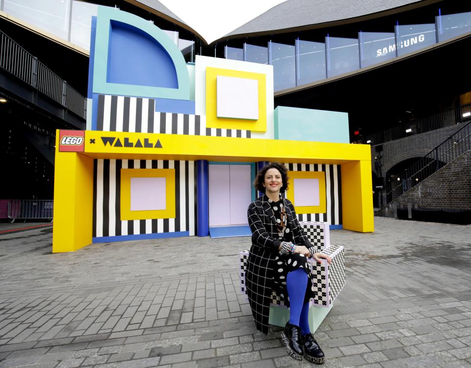 Camille Walala poses in front of her colorful HOUSE OF DOTS installation with LEGO at Coal Drops Yard, London.