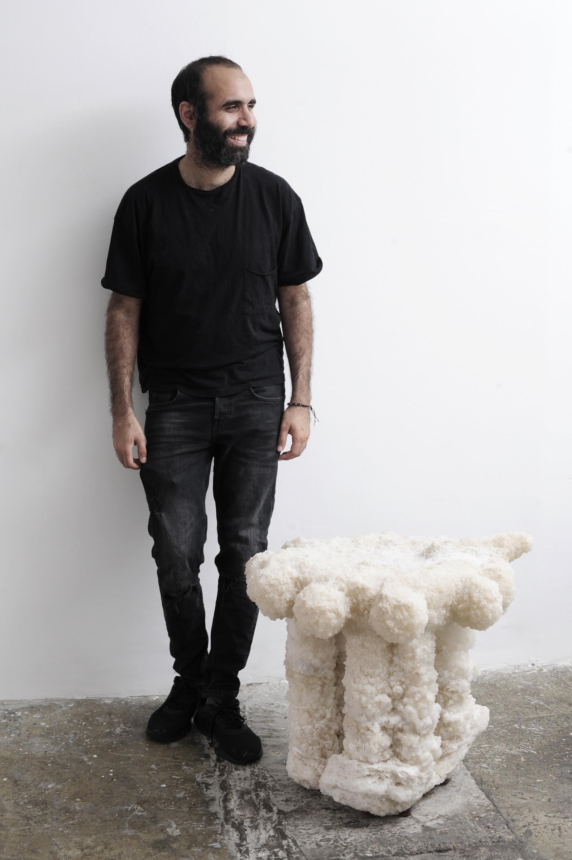 Erez Nevi Pana stands beside innovative vegan furniture made from Dead Sea minerals, showcasing sustainable design principles.