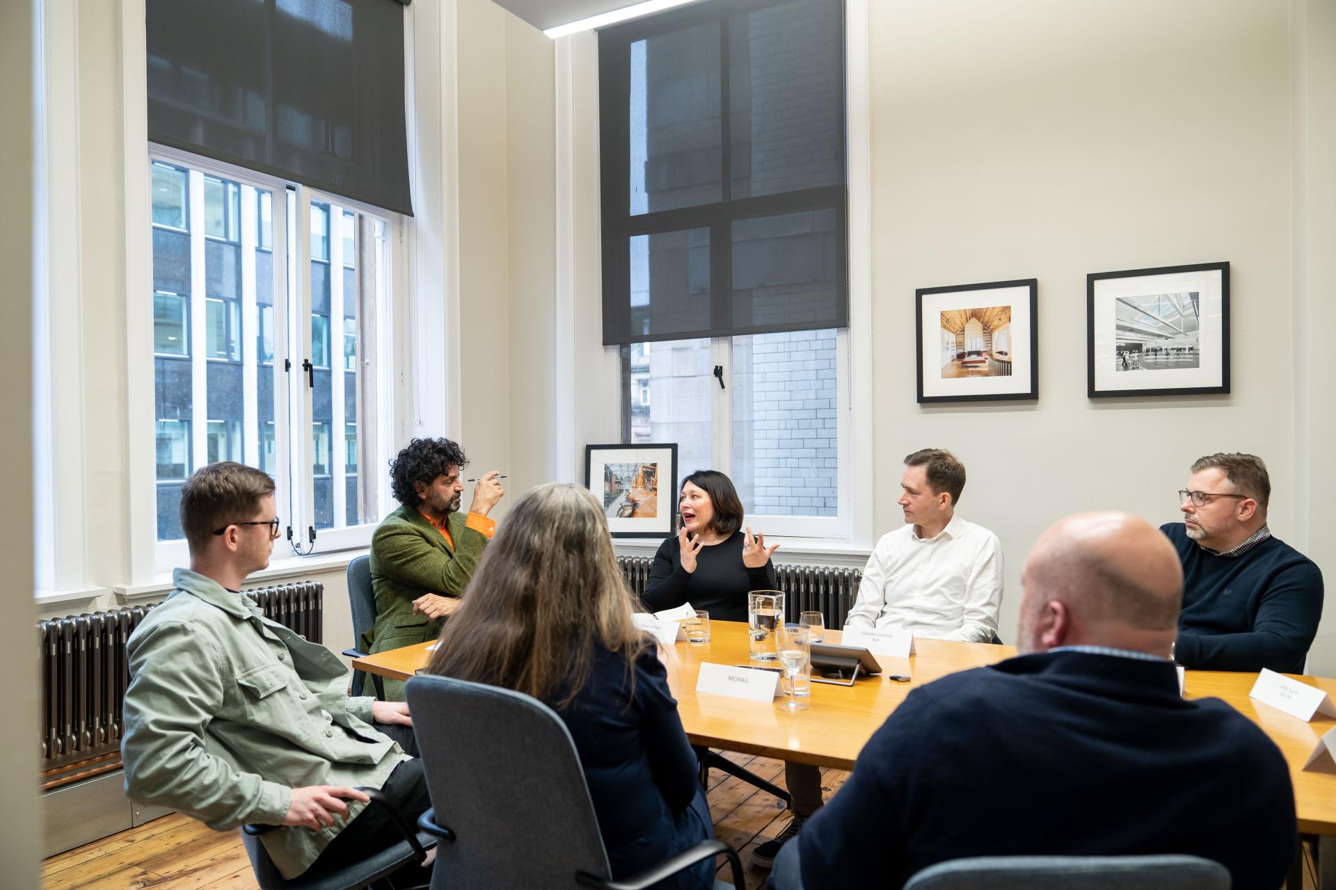 Professionals engage in discussion at a sustainability seminar, focusing on climate crisis solutions in a modern meeting space.