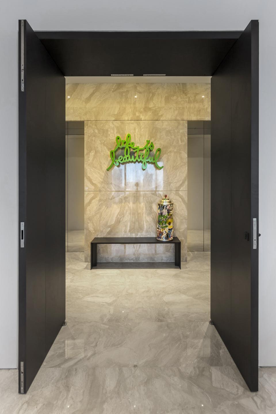 Stylish entryway of Elliot James' award-winning Cuscaden One apartment, featuring modern decor and a vibrant green wall art.