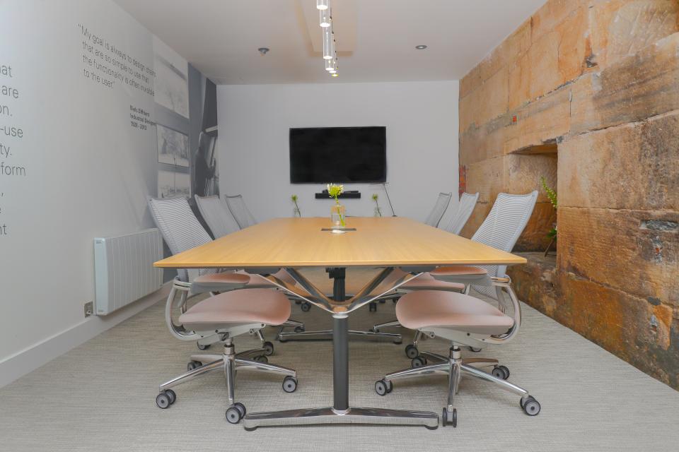 Modern conference room in Humanscale's Manchester showroom featuring ergonomic chairs and a large wooden table.