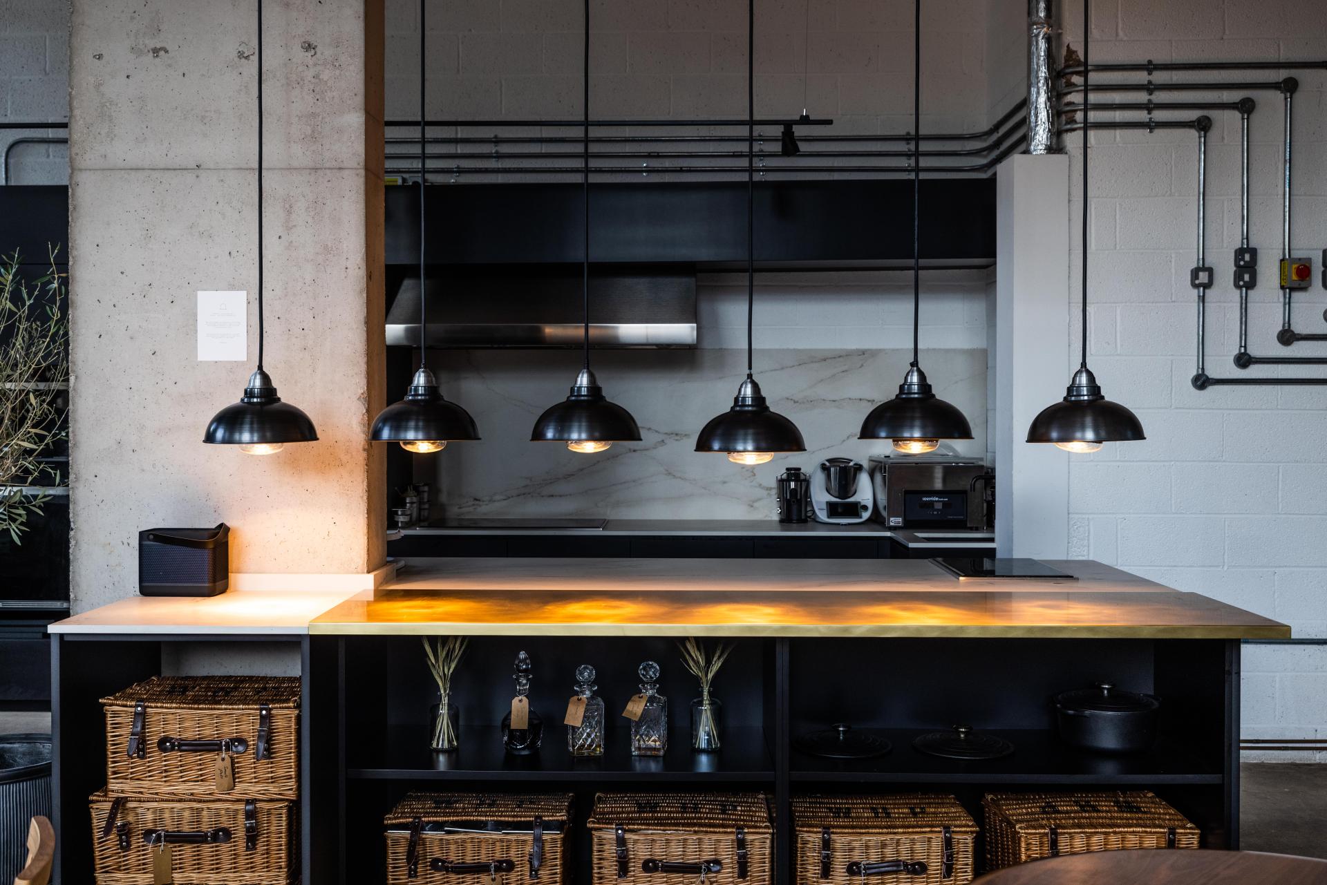 Sophisticated kitchen interior with Dekton® surfaces, pendant lights, and elegant storage at The Water House Project restaurant.