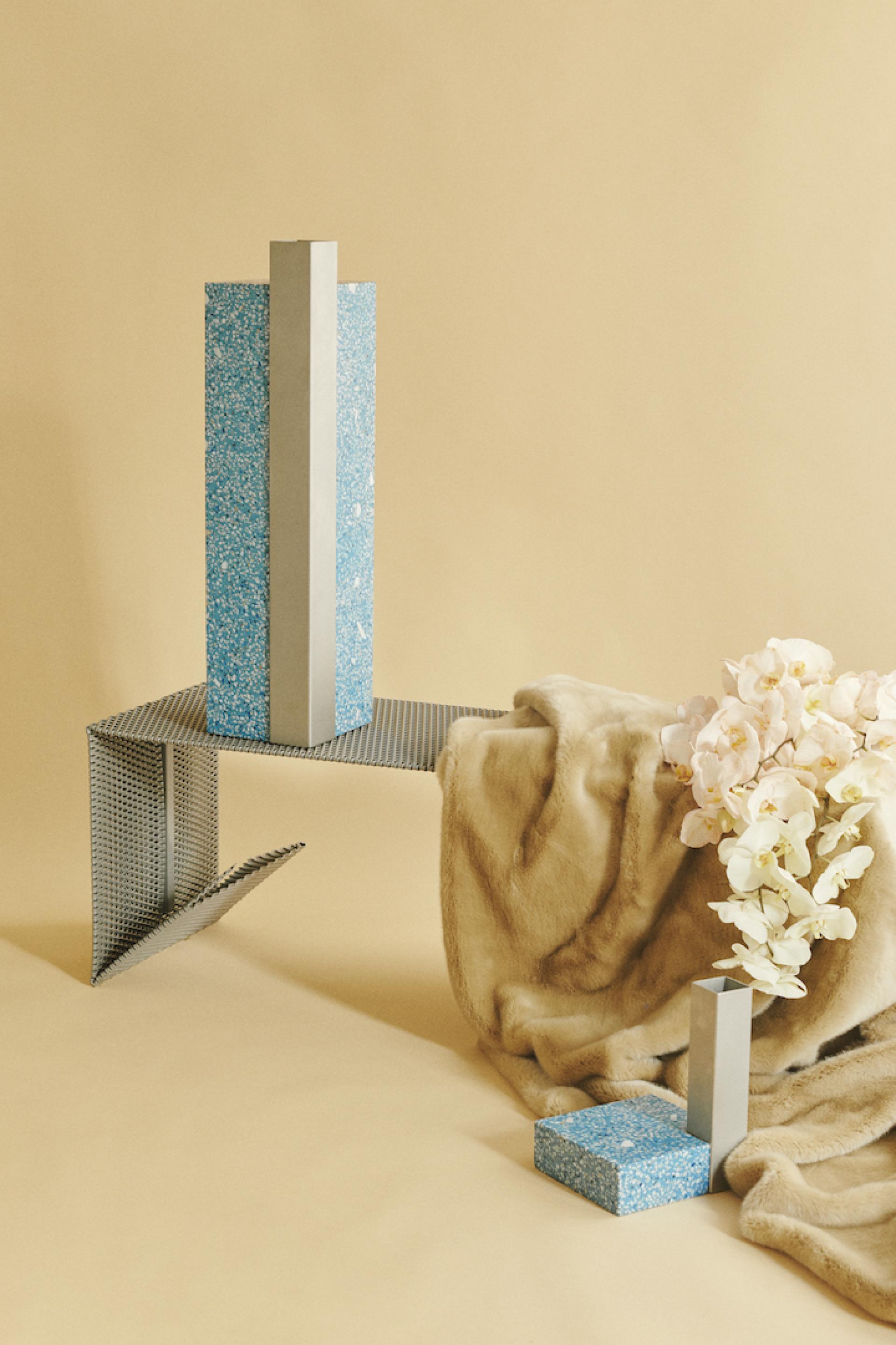 Modern design display featuring geometric vases, fabric drapes, and fresh flowers in a minimalist setting by Tableau, Copenhagen.