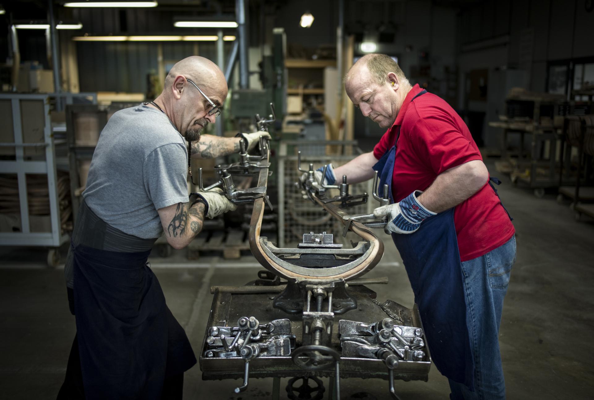 Workers collaborate in a German manufacturing facility to craft furniture, showcasing efficient short supply chain practices.