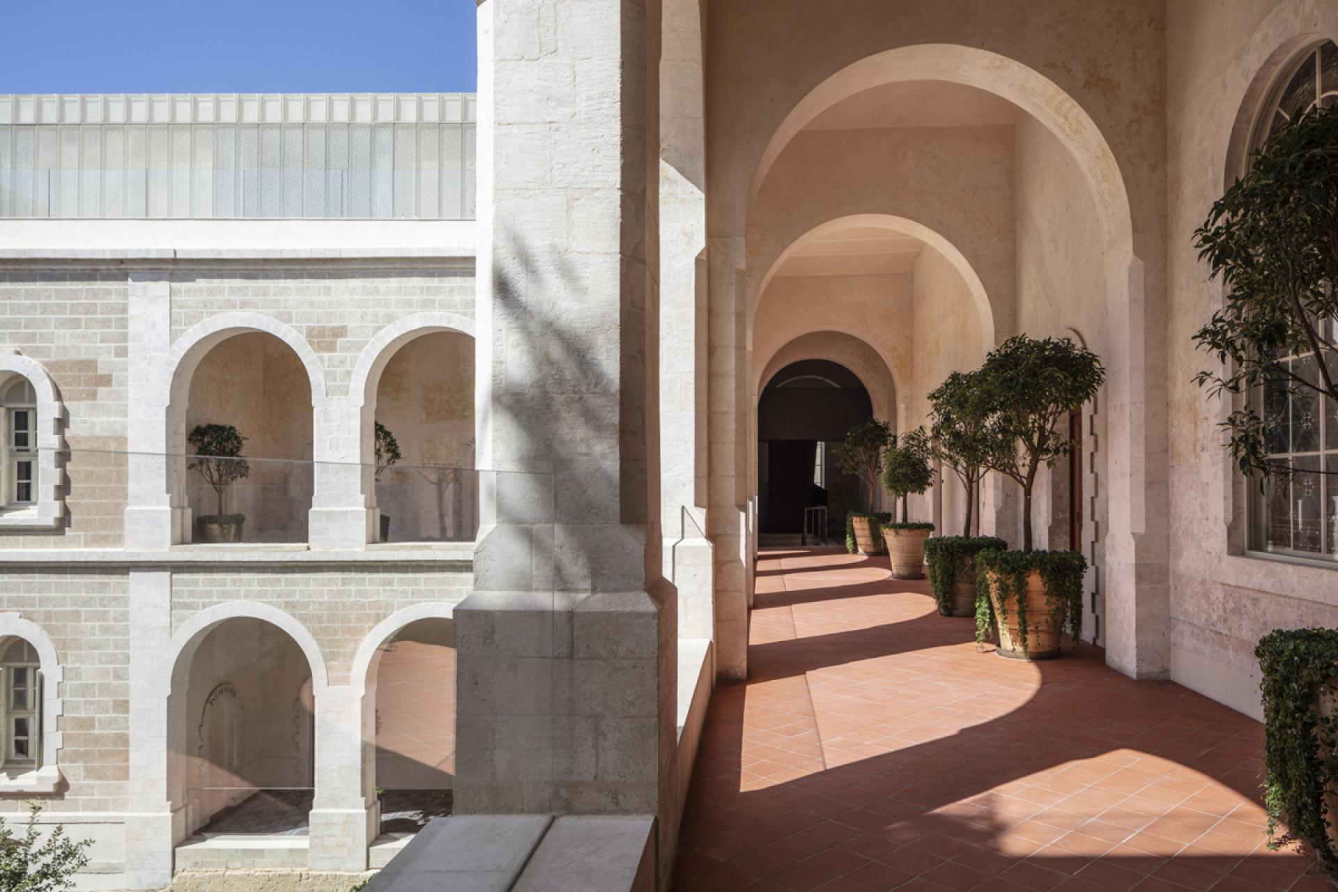 Elegant arched corridors with minimalist design and potted greenery at The Jaffa, showcasing John Pawson's architectural style.
