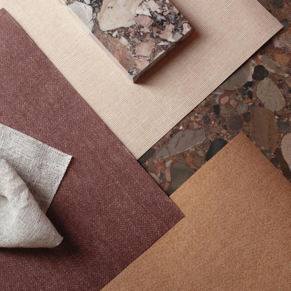 Textured wallcovering samples in rich colors, including burgundy, beige, and orange, showcasing Arte's 2025 spring collection.