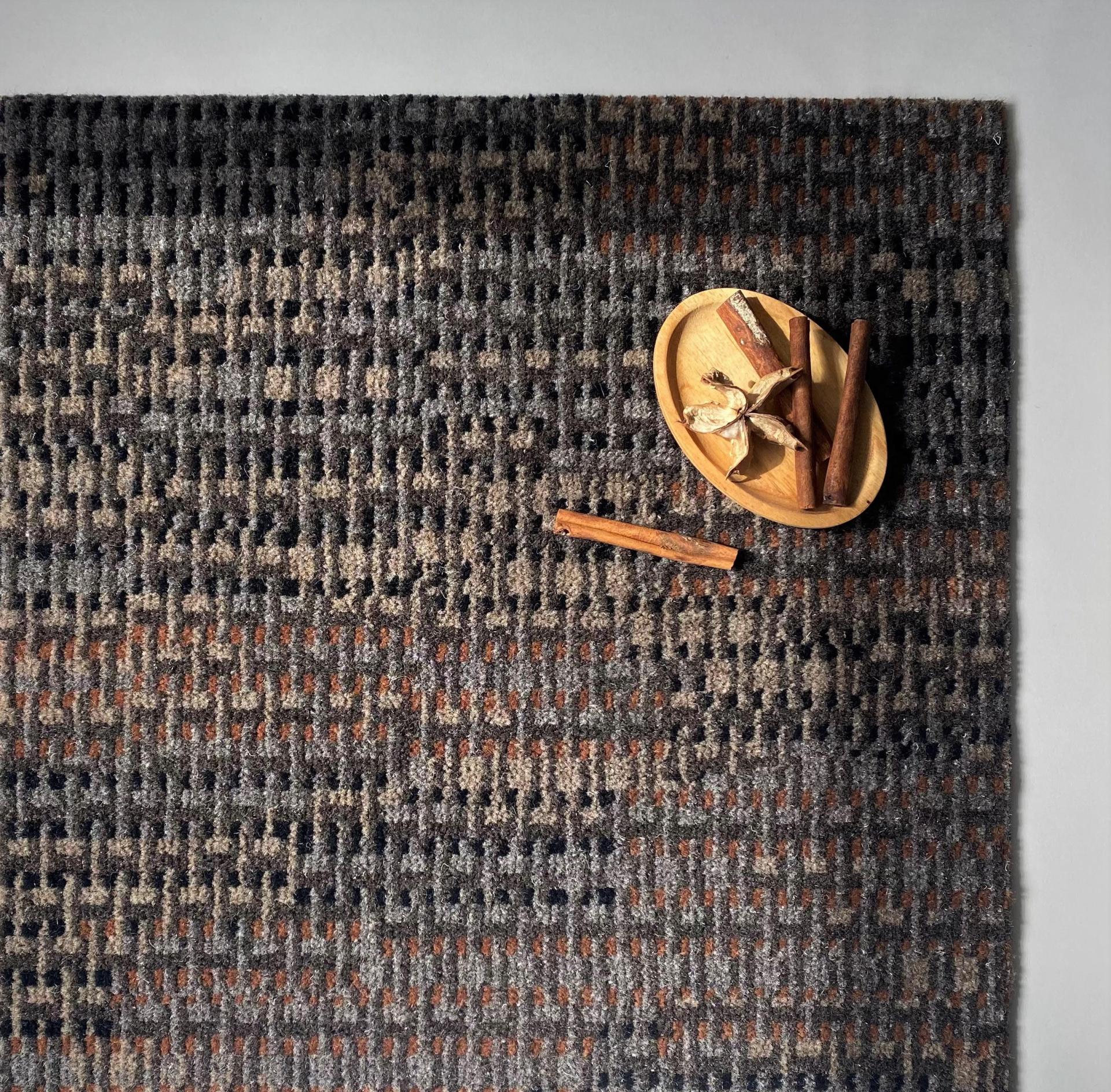 Textured macrame carpet from Newhey Carpets with earthy tones, accompanied by a decorative wooden bowl and spices.