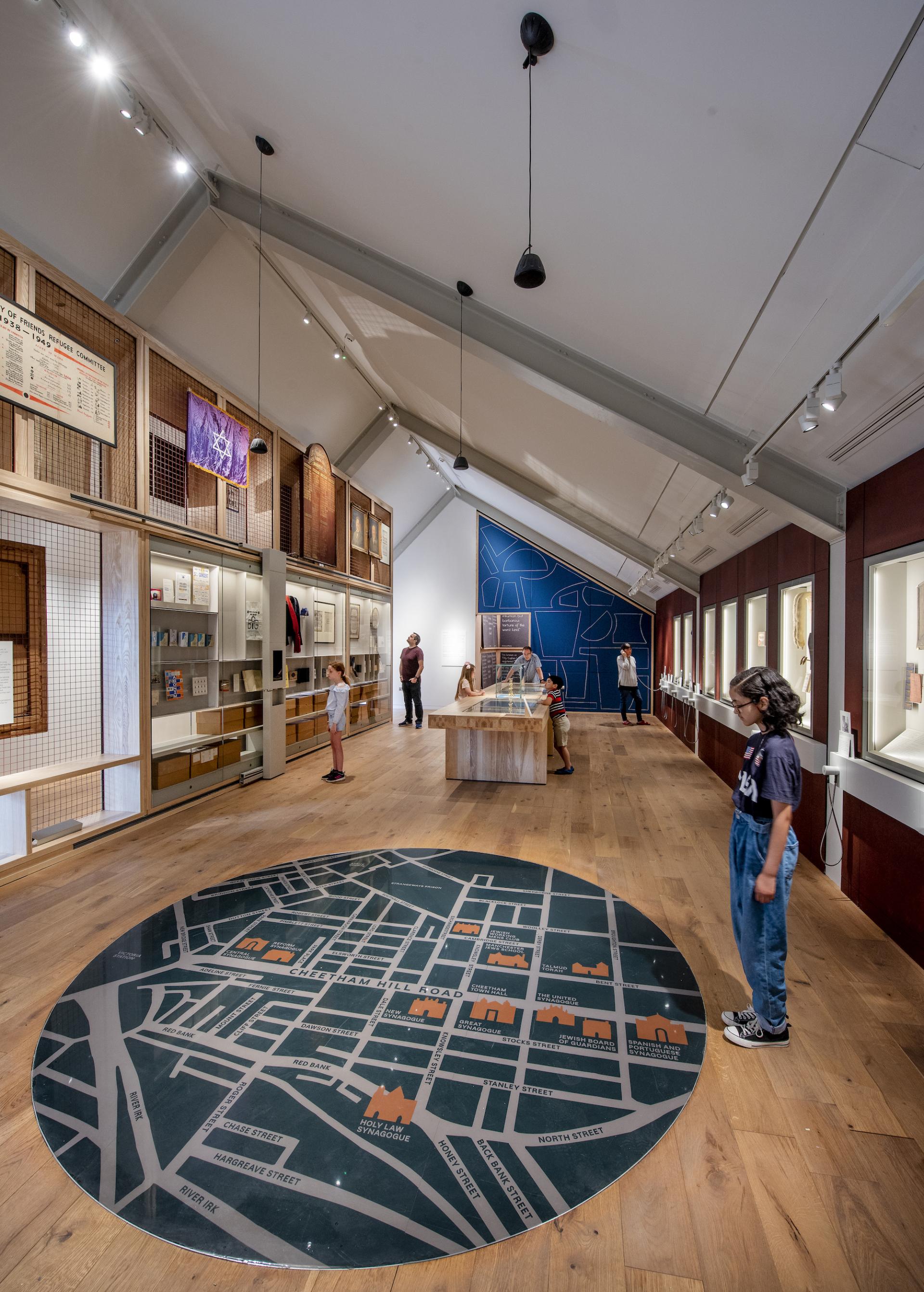 Visitors explore the Manchester Jewish Museum's new extension featuring a map installation and cultural exhibits.