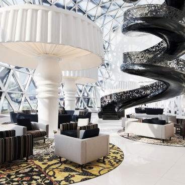 Luxurious lounge area in Mondrian Doha featuring striking spiral staircase and unique lighting design by Marcel Wanders.
