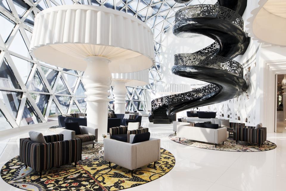 Luxurious lounge area in Mondrian Doha featuring striking spiral staircase and unique lighting design by Marcel Wanders.