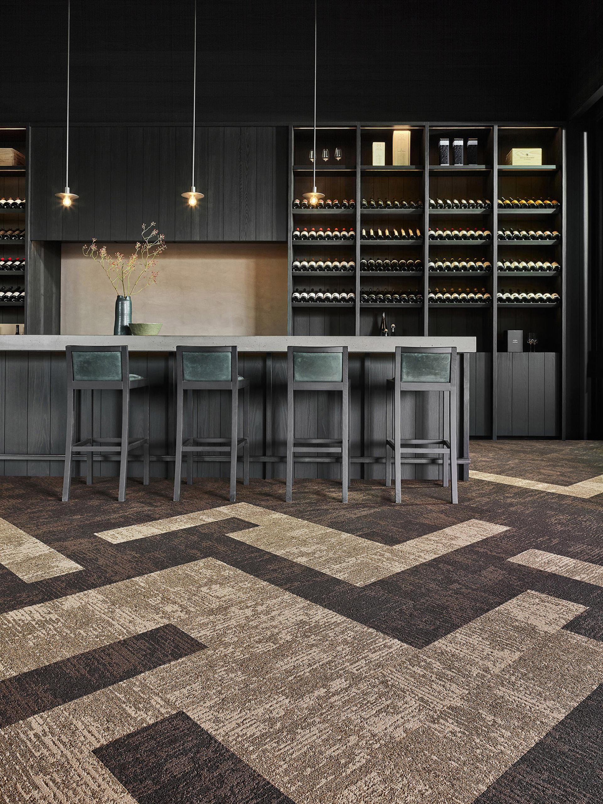 Modern kitchen with textured flooring, minimalist bar seating, and stylish wine storage, embracing the beauty of imperfection.
