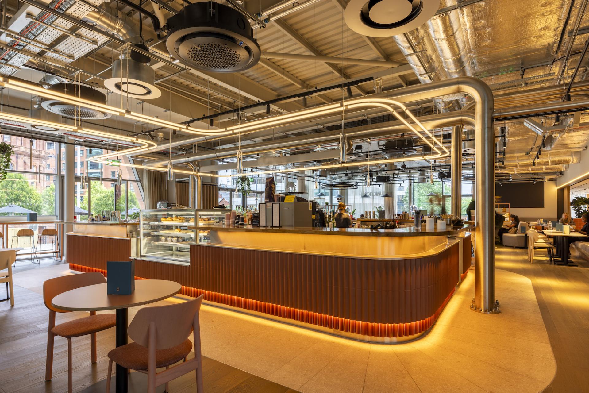 Stylish interior of a modern cafe with illuminated curved bar, industrial design elements, and guests enjoying the atmosphere.