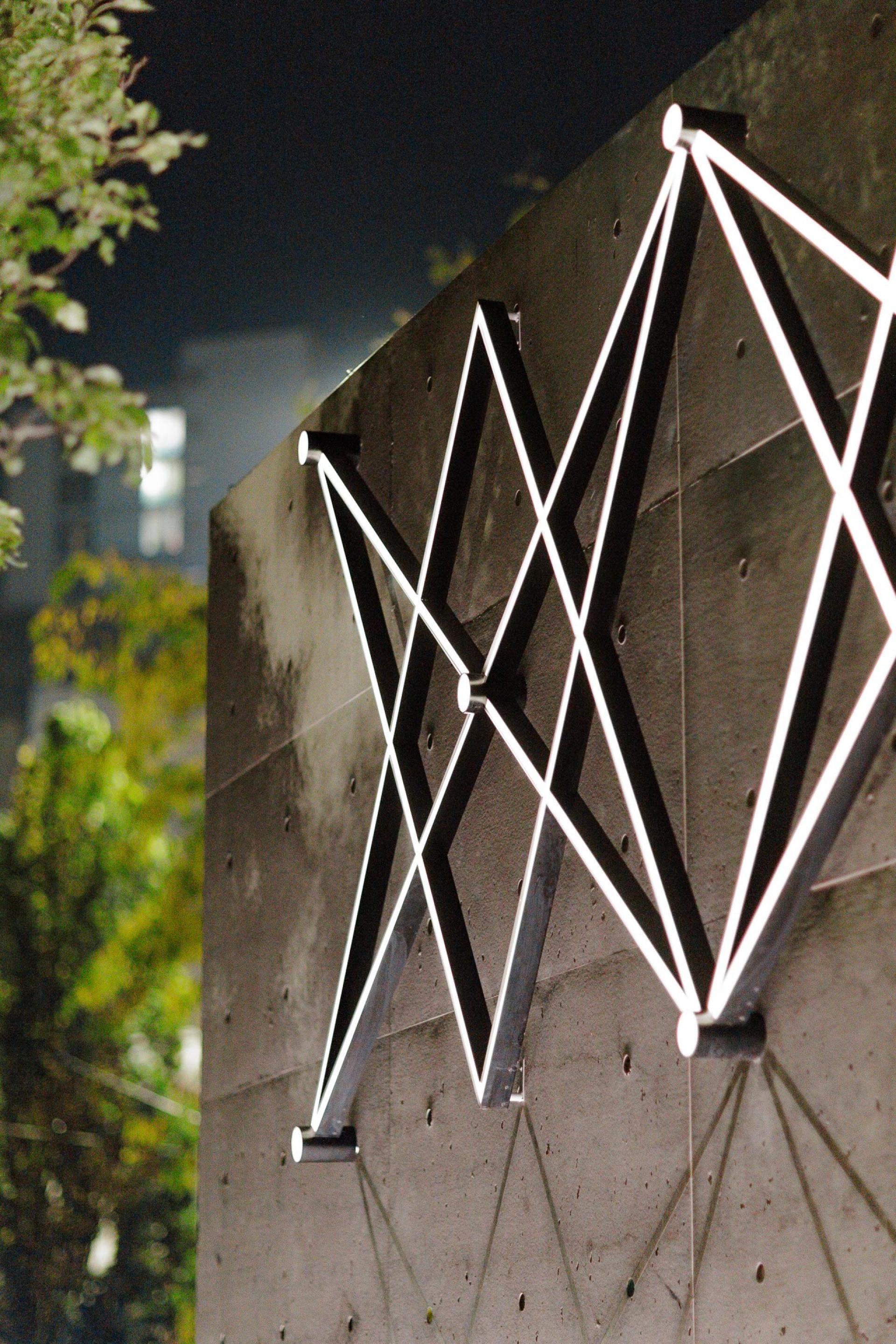 Illuminated geometric design on a concrete wall in Manchester’s Piccadilly Gardens Pavilion at night, highlighting creative architecture.