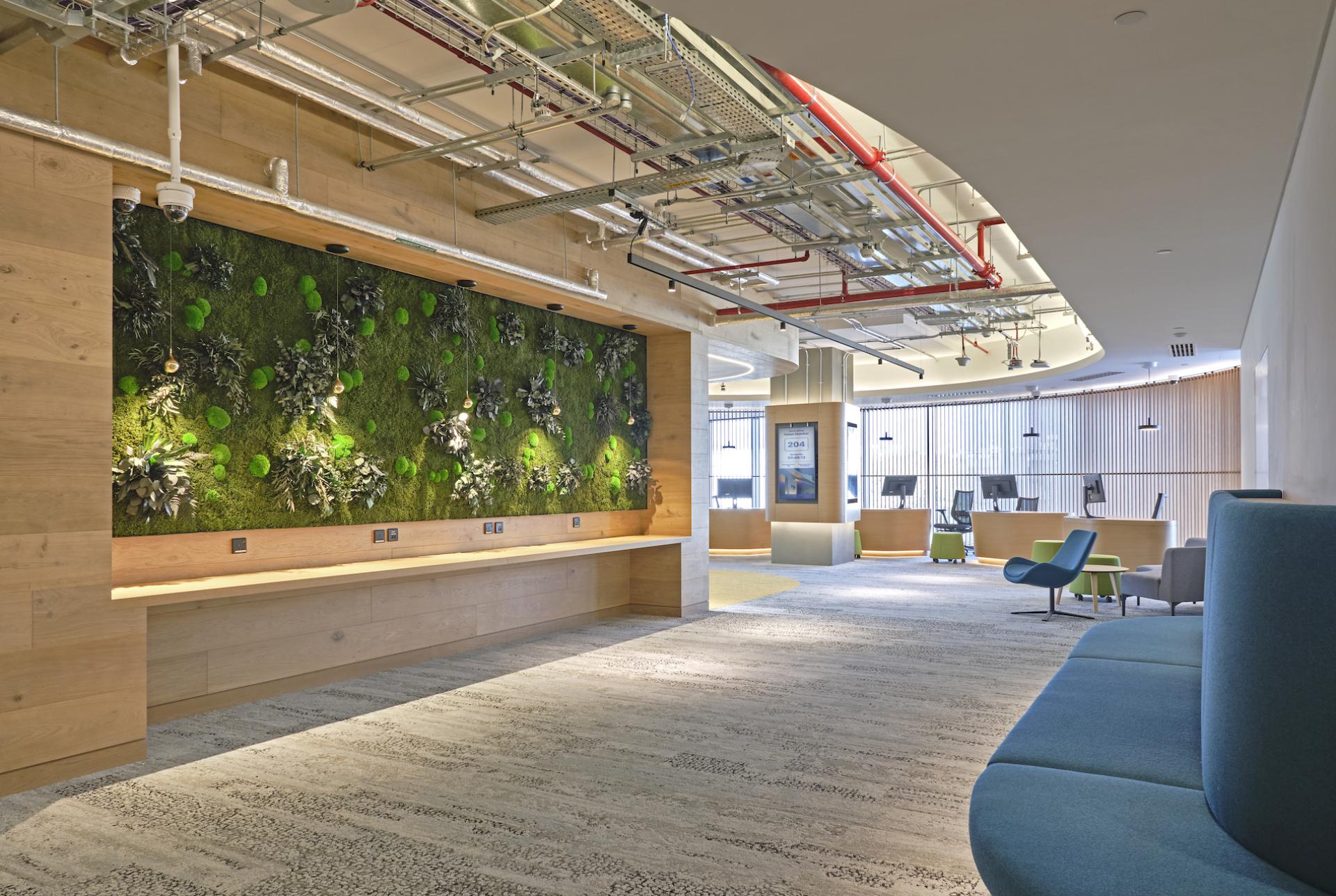 Modern interior of Heriot-Watt University's Dubai campus featuring a green wall, open space, and contemporary furnishings.