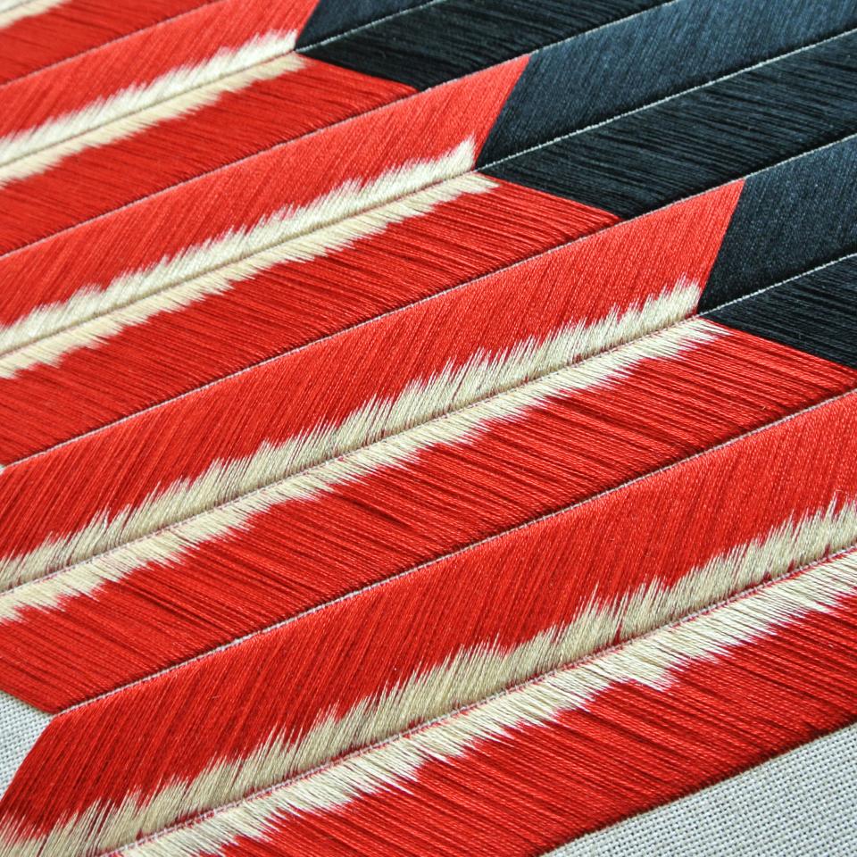 Traditional Slovakian embroidery featuring vibrant red and black threads in a contemporary geometric design.
