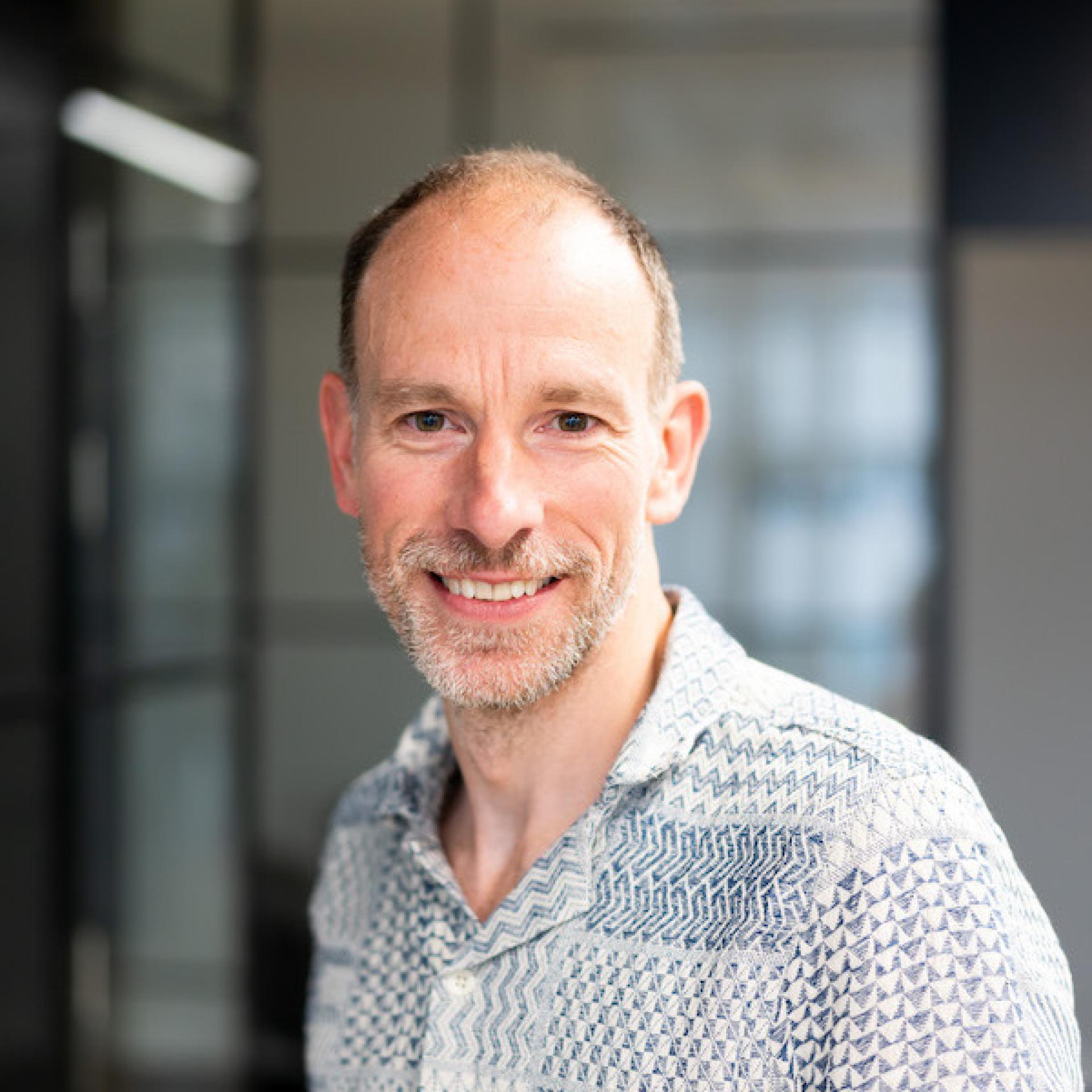 Smiling professional in a modern workspace, representing innovative technology in forward-thinking workplaces.