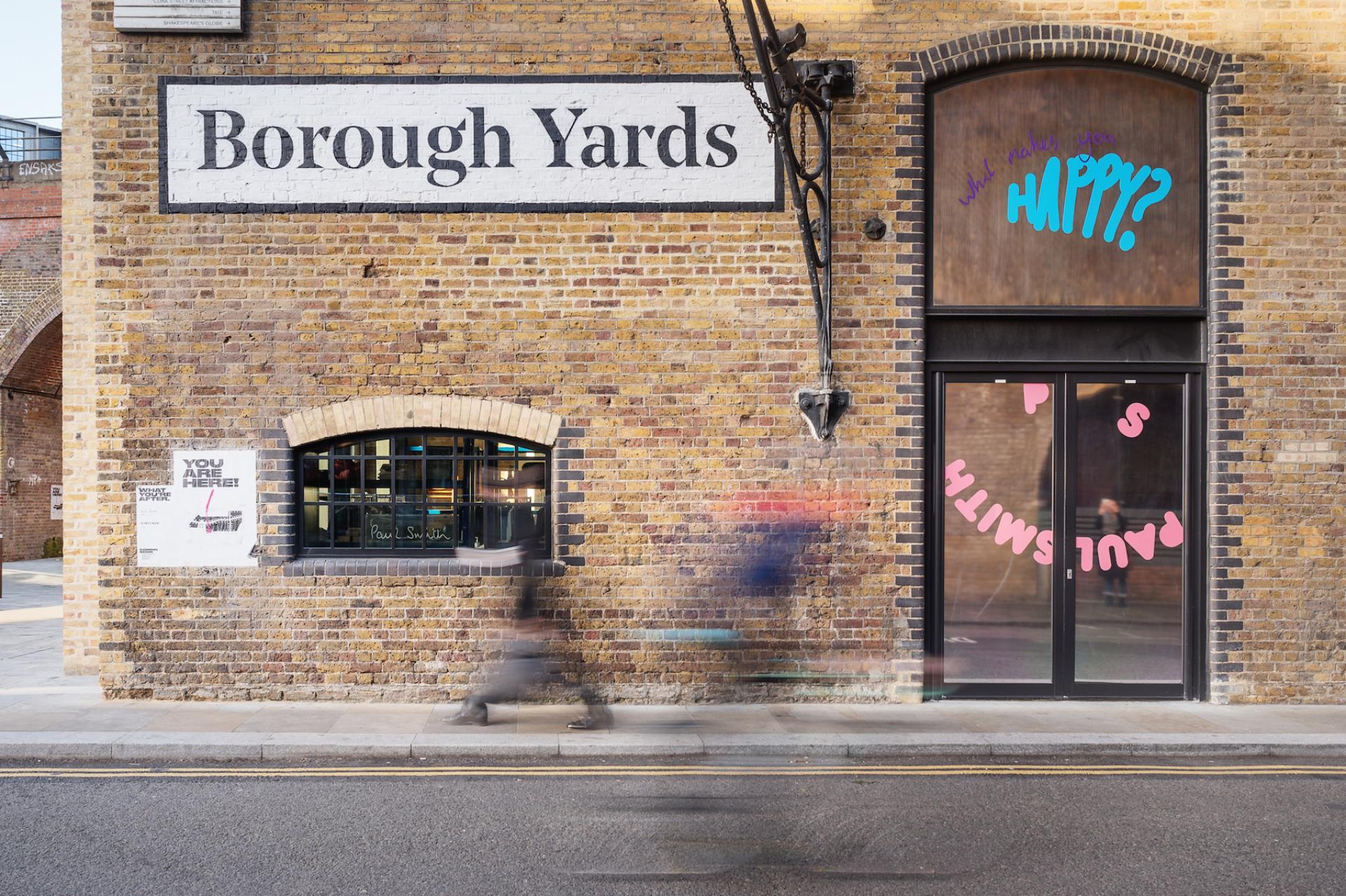 Brick facade of Borough Yards featuring colorful signage and window displays, capturing the essence of London's vibrant cultural scene.