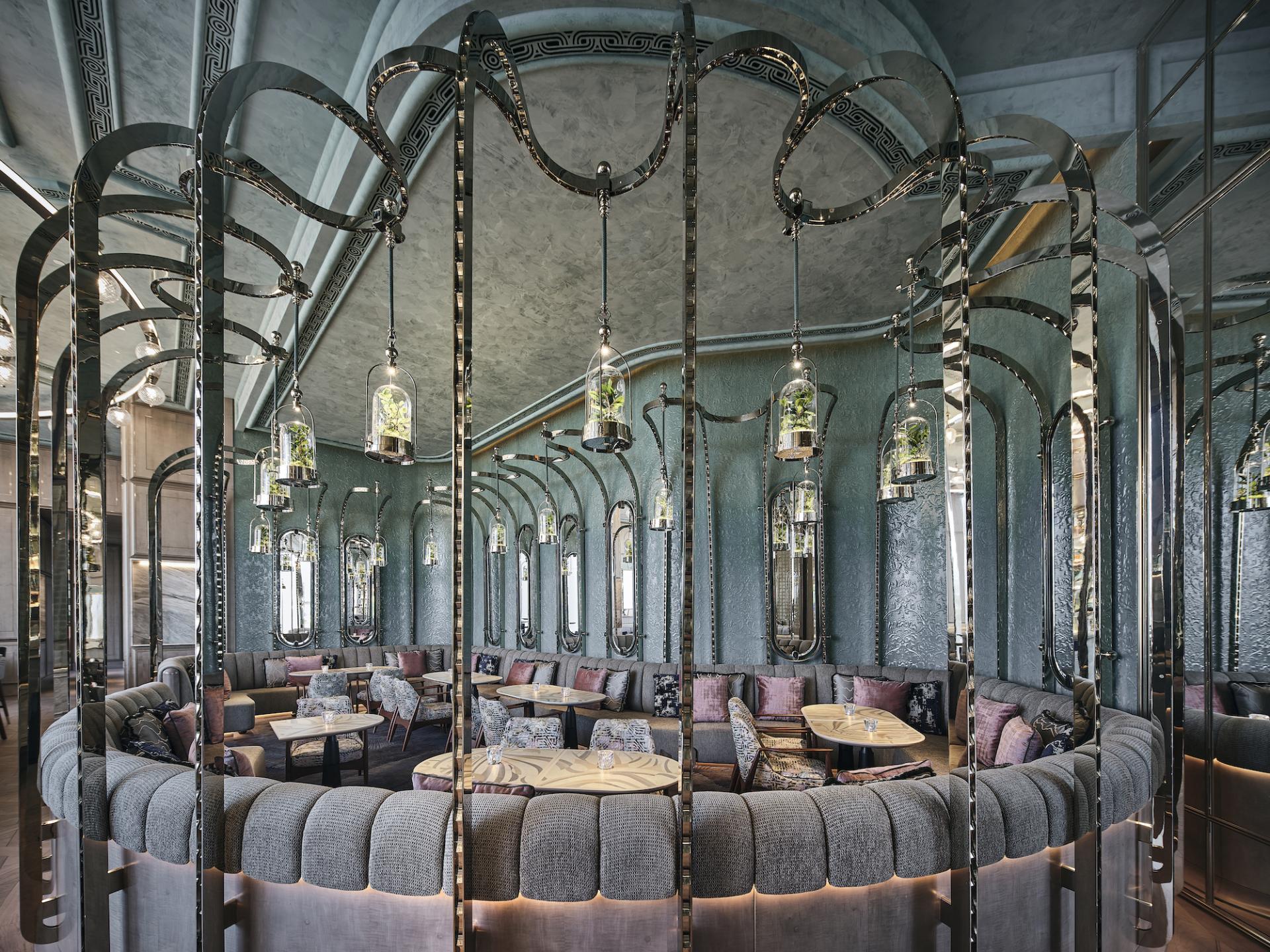 Stylish interior of Argo bar featuring plush seating, decorative lighting, and lush greenery, designed by AB Concept.