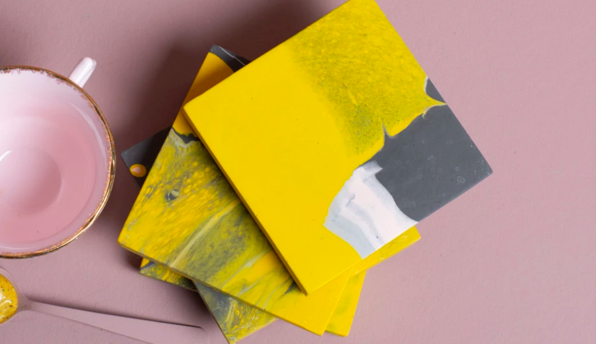 Colorful handmade coasters in yellow and gray, alongside a pink bowl, showcasing Manchester's vibrant craft scene.