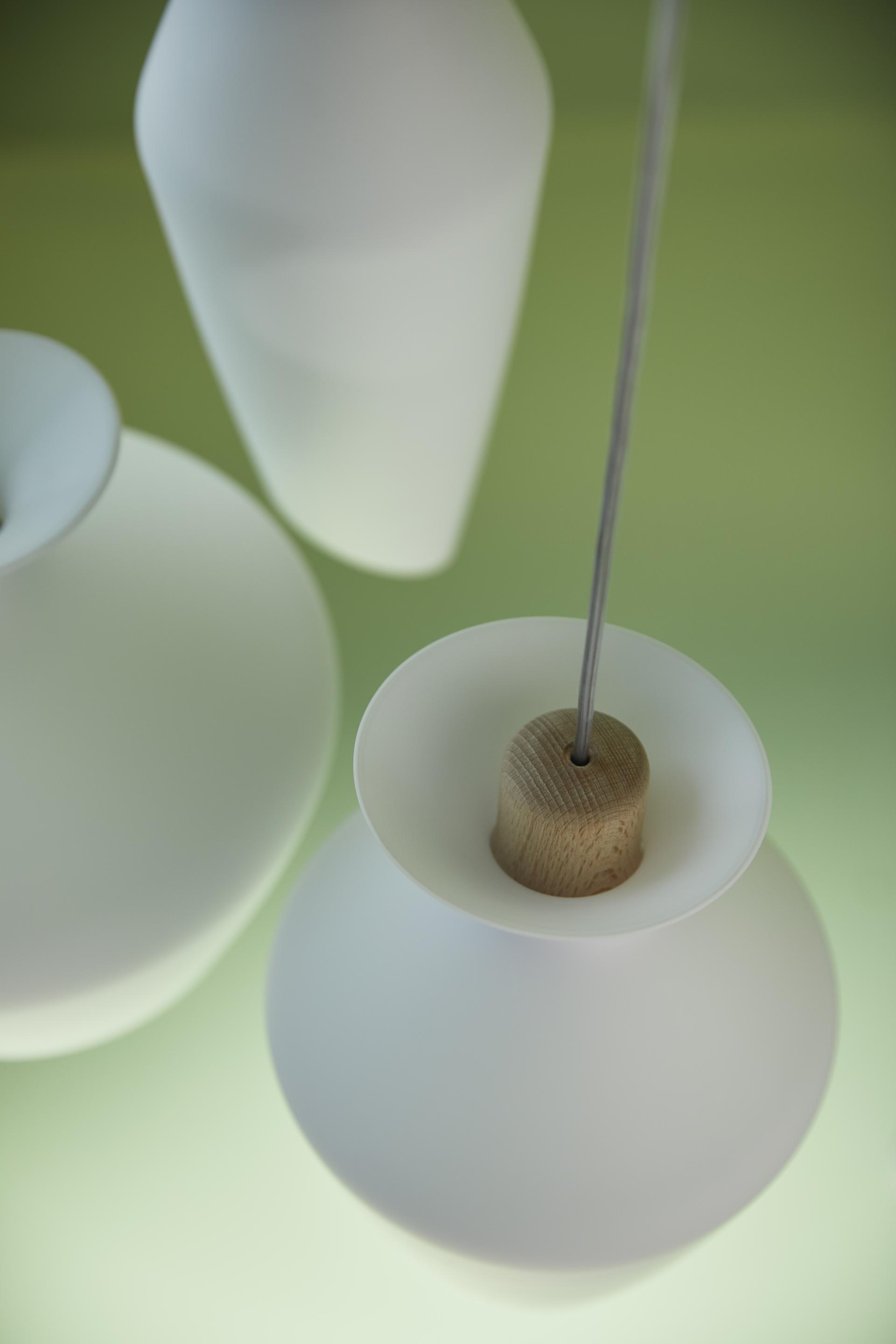Blown glass lamps from Fabbian, showcasing rounded shapes and wooden accents, create a harmonious illumination effect.